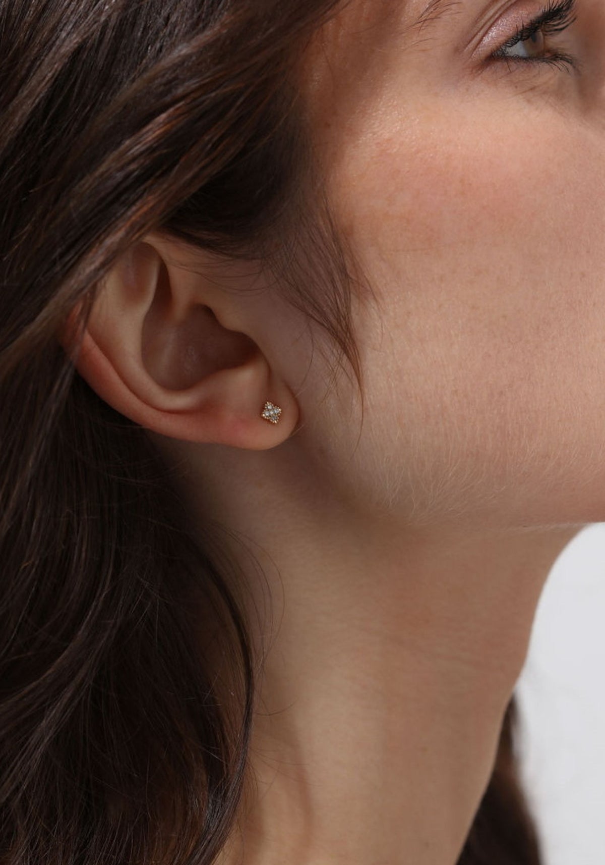 La femme porte la boucle d'oreille puce en or jaune Nina One de chez Angèle Brousse