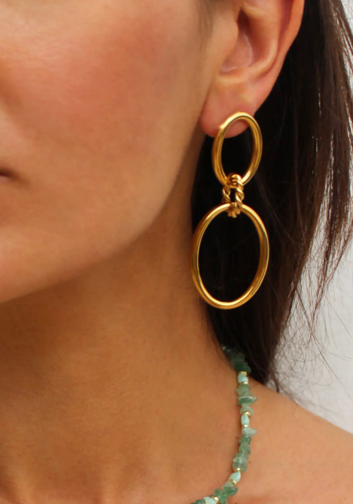 La femme porte les boucles d'oreilles Alba de chez Caprice Paris