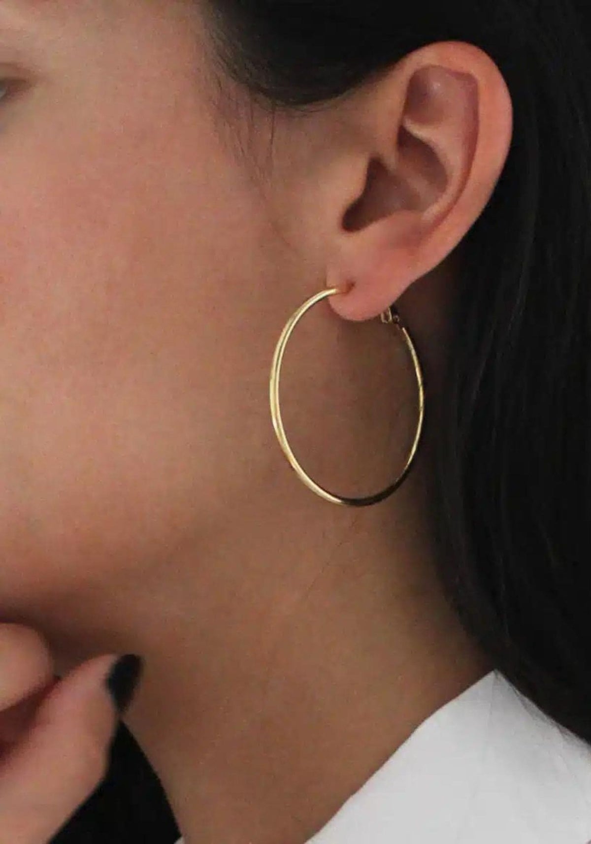 La femme porte les boucles d'oreilles créoles Sabrina de chez Caprice Paris