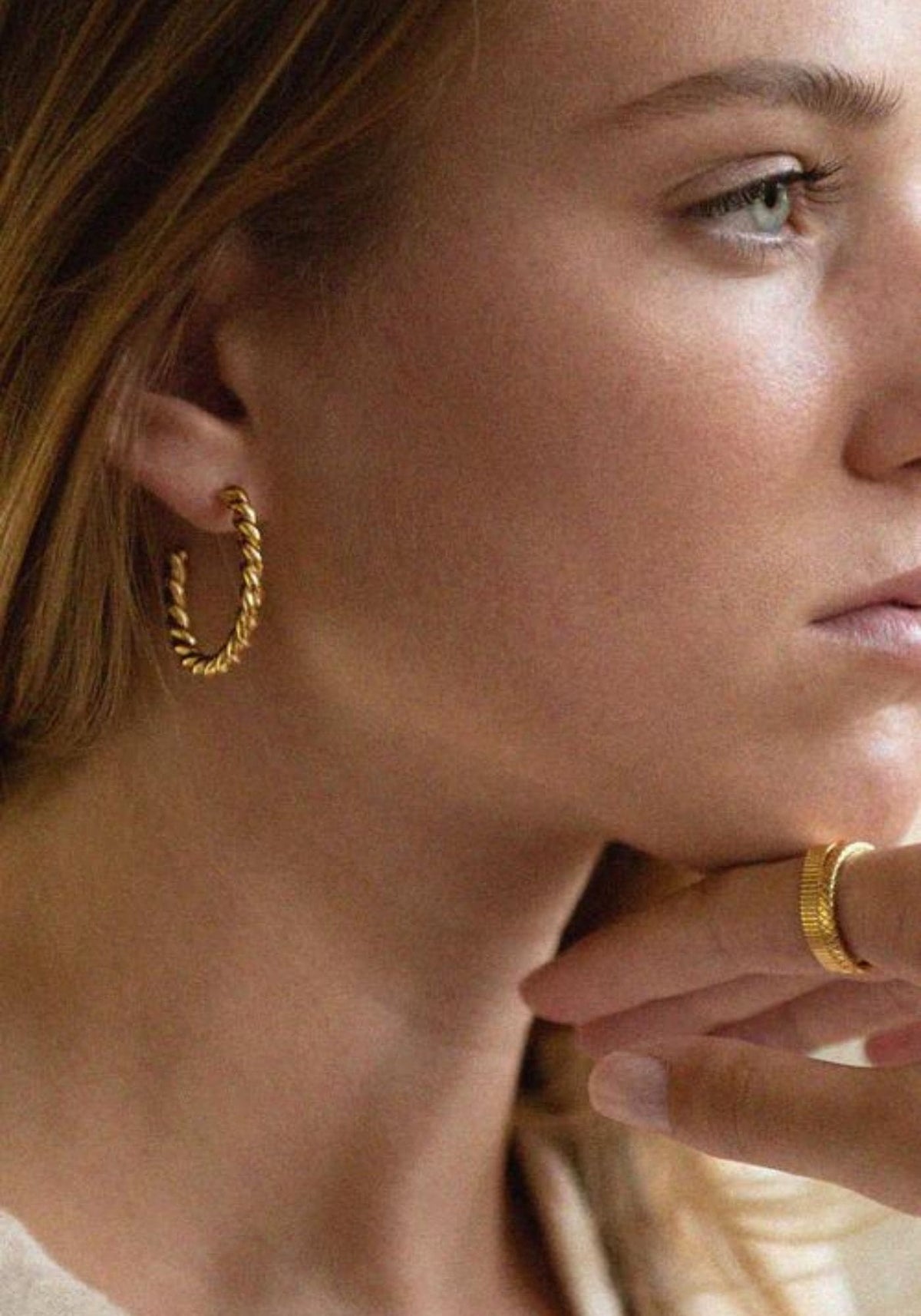 La femme porte les boucles d'oreilles Gabrielle de chez Bacci Paris