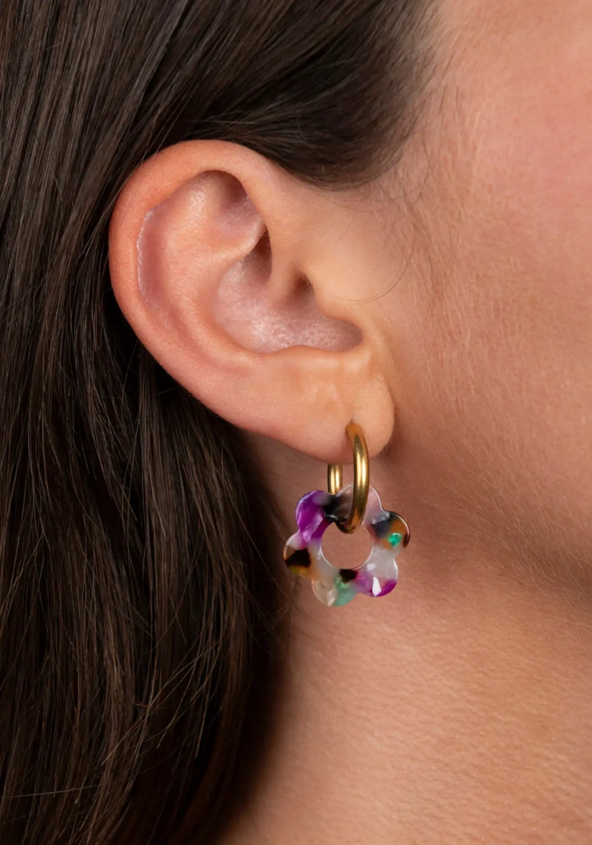 La femme porte les boucles d'oreilles fleurette confettis baby de chez Kurage Ginza