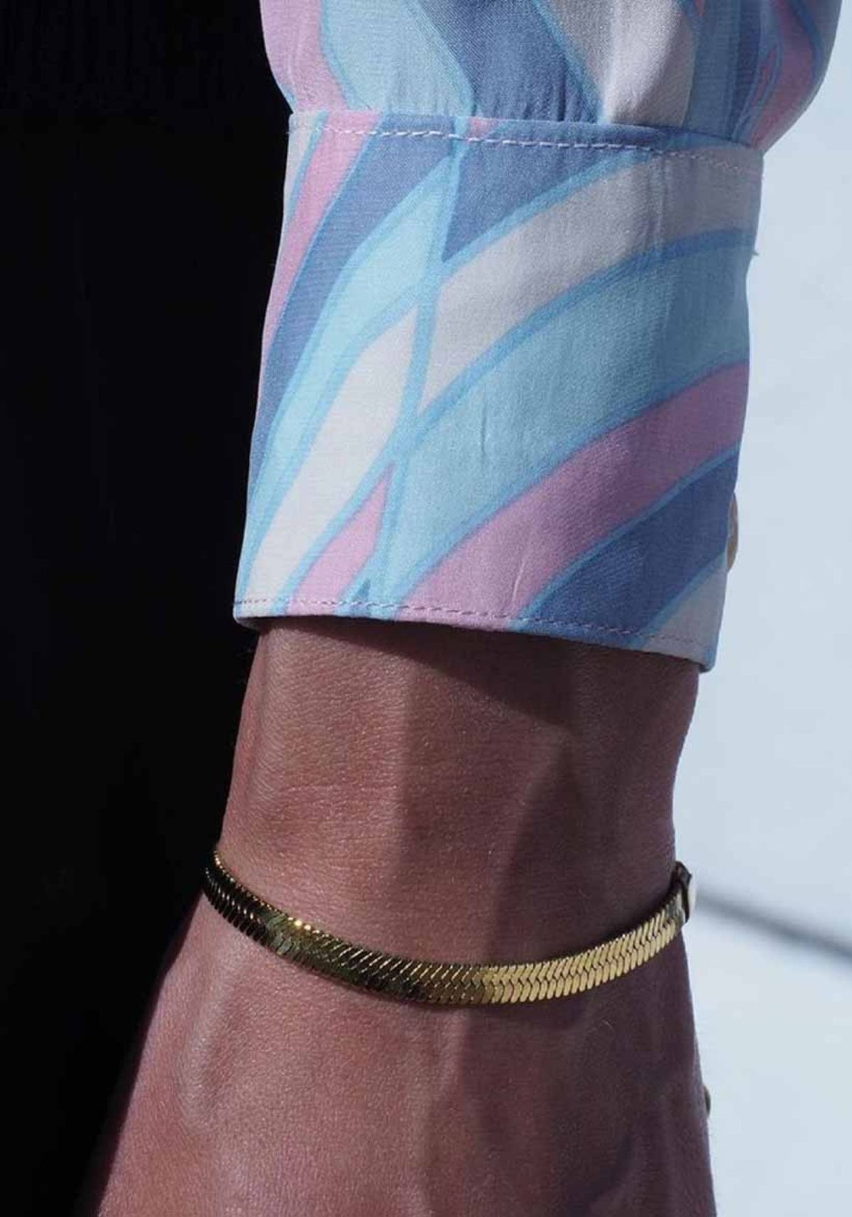 La femme porte au poignet le bracelet Leto en doré de chez Caprice Paris