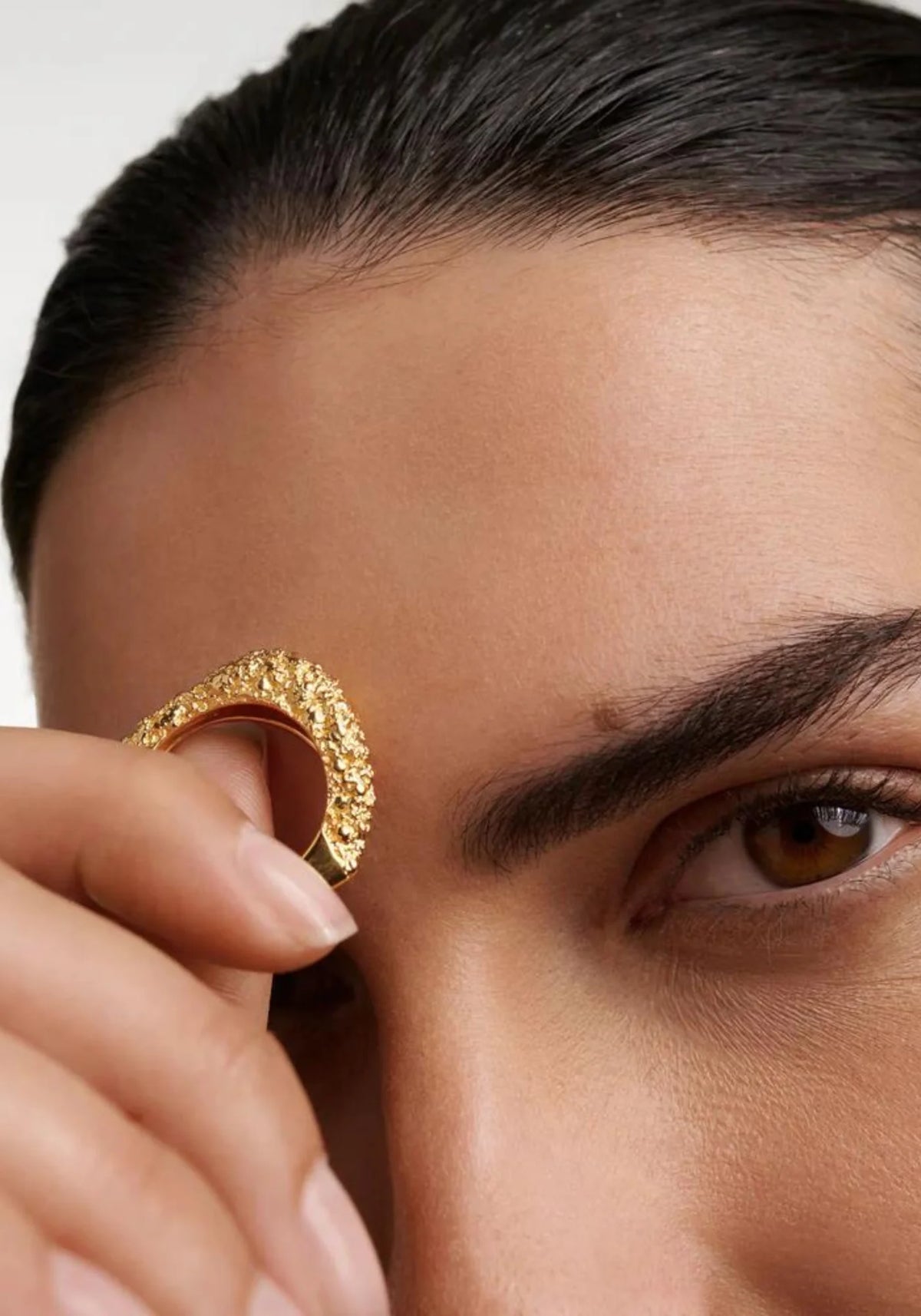 La femme tient entre ses doigts la bague en or jaune 18 carats Duna de chez PD Paola