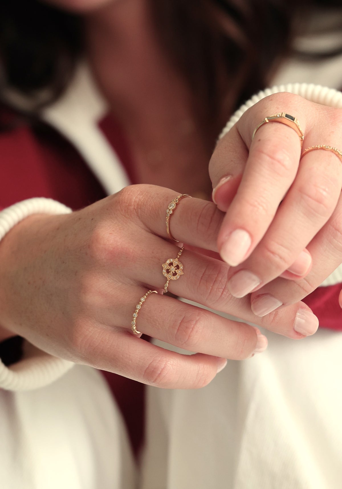 La femme a les mains légèrement entrecroisées et porte la bague en or jaune Gina Star de chez Angèle Brousse à son majeur