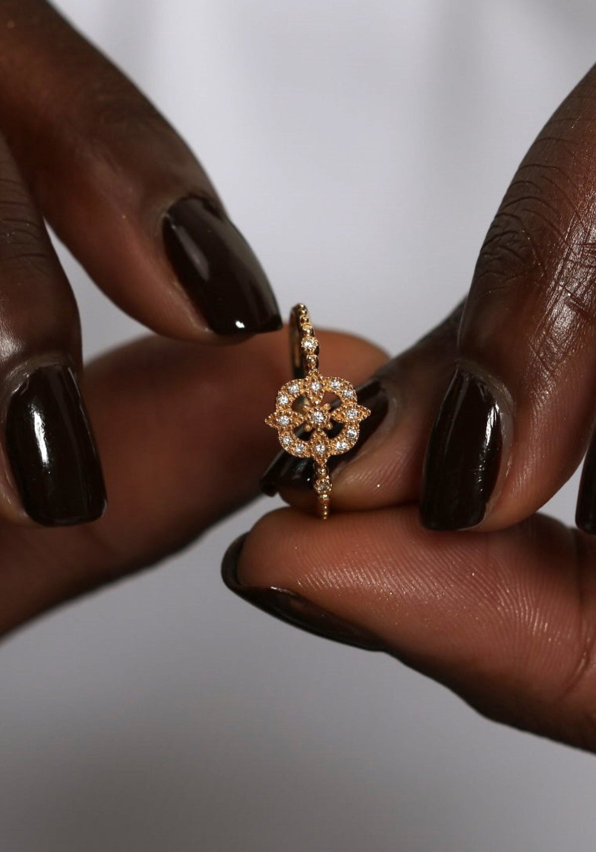 La femme tient entre ses doigts la bague en or jaune Gina Star de chez Angèle Brousse