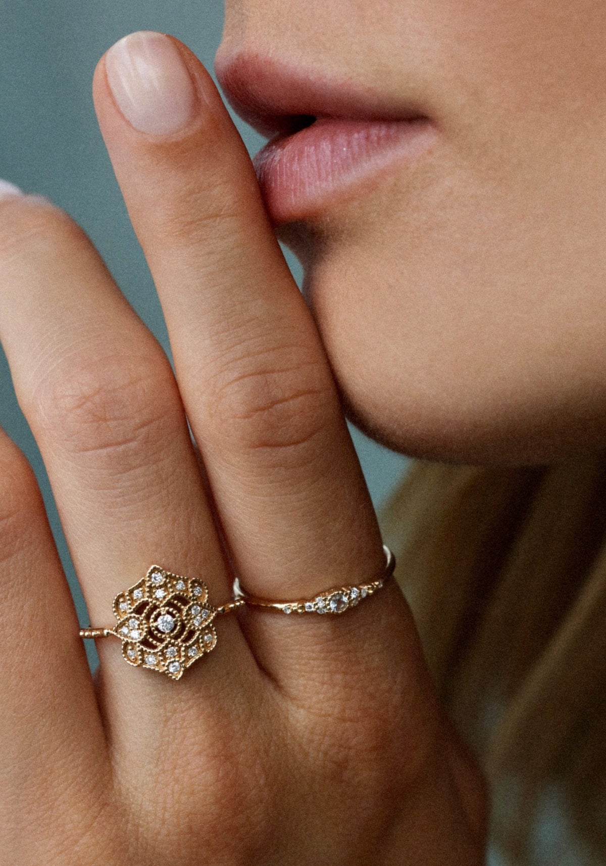 La femme porte le doigt à sa bouche et porte la bague en or jaune Shiny Paradis de chez Angèle Brousse à son majeur