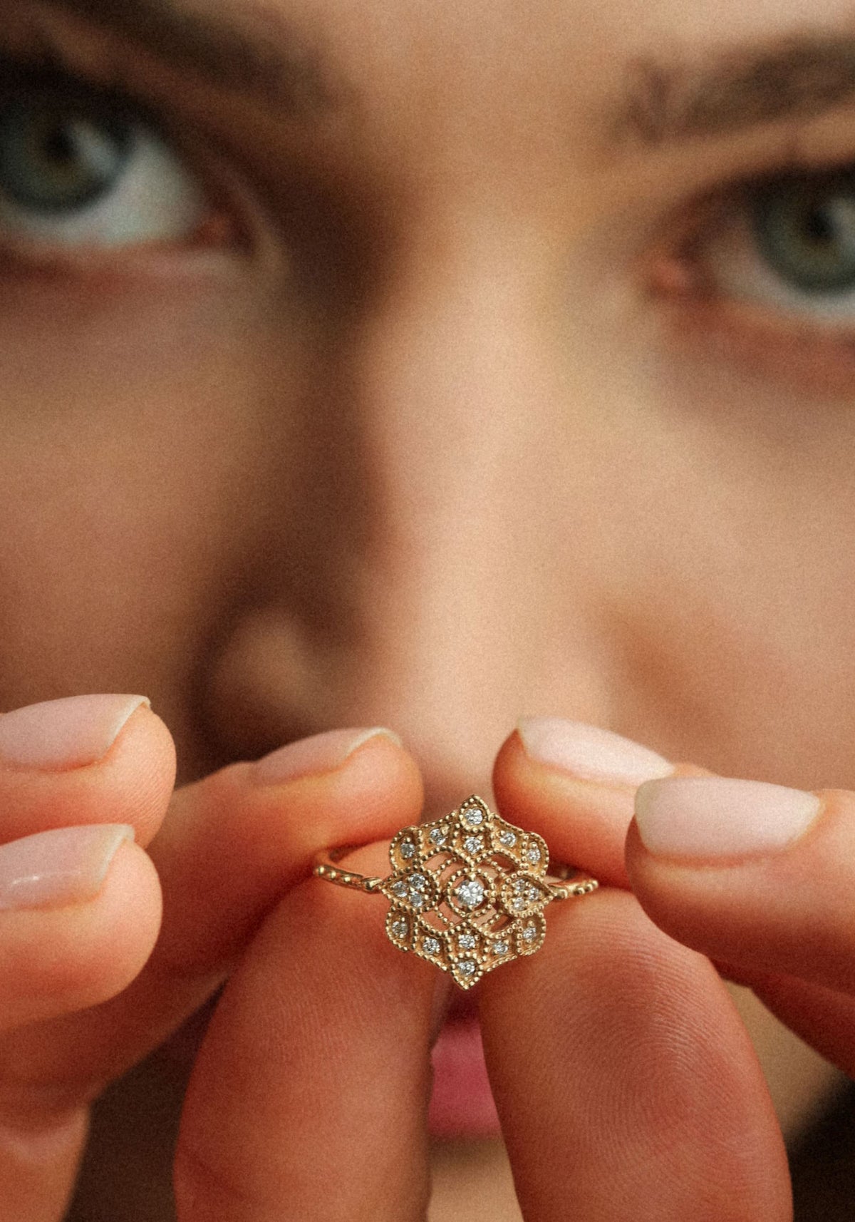 La femme tient entre ses doigts la bague en or jaune Shiny Paradis de chez Angèle Brousse