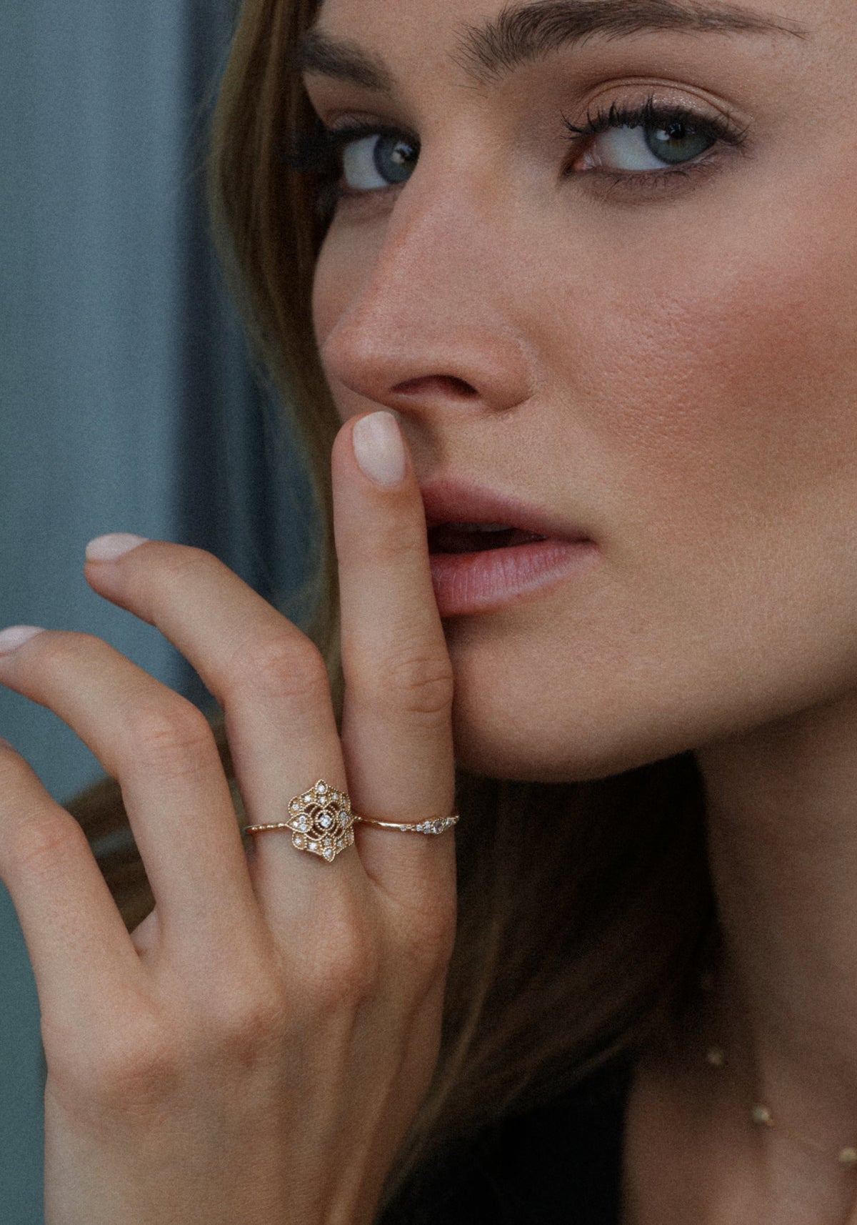 La femme porte le doigt à sa bouche et porte la bague en or jaune Shiny Paradis de chez Angèle Brousse à son majeur