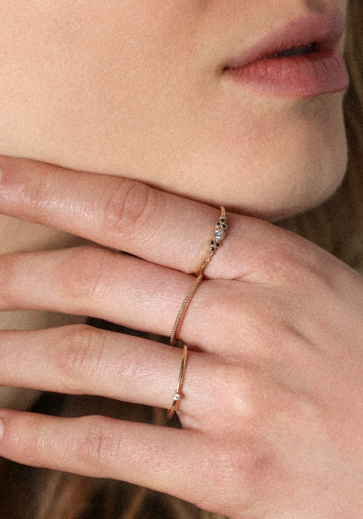 La femme porte la bague Little Paradis Diamants Noirs de chez Angèle Brousse en ayant la main au niveau de son menton.