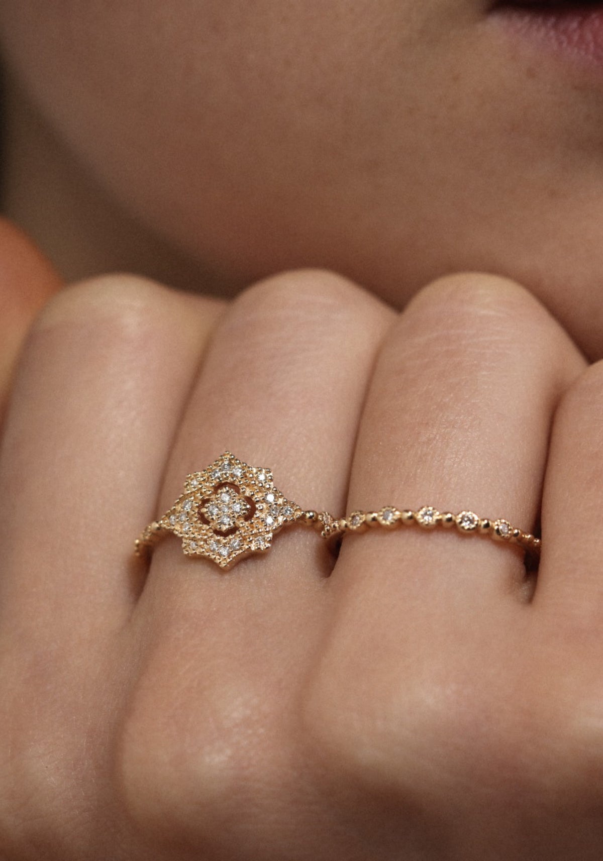La femme porte la bague Nina Small en or jaune de chez Angèle Brousse en ayant la main posée sous son menton.