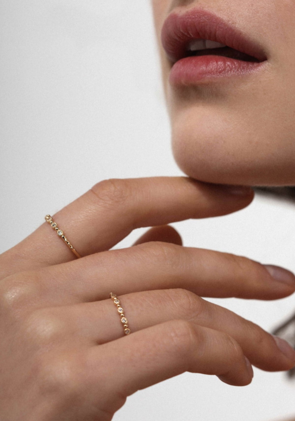 La femme porte la bague Nina Small en or jaune de chez Angèle Brousse en ayant l'index posé sous son menton.