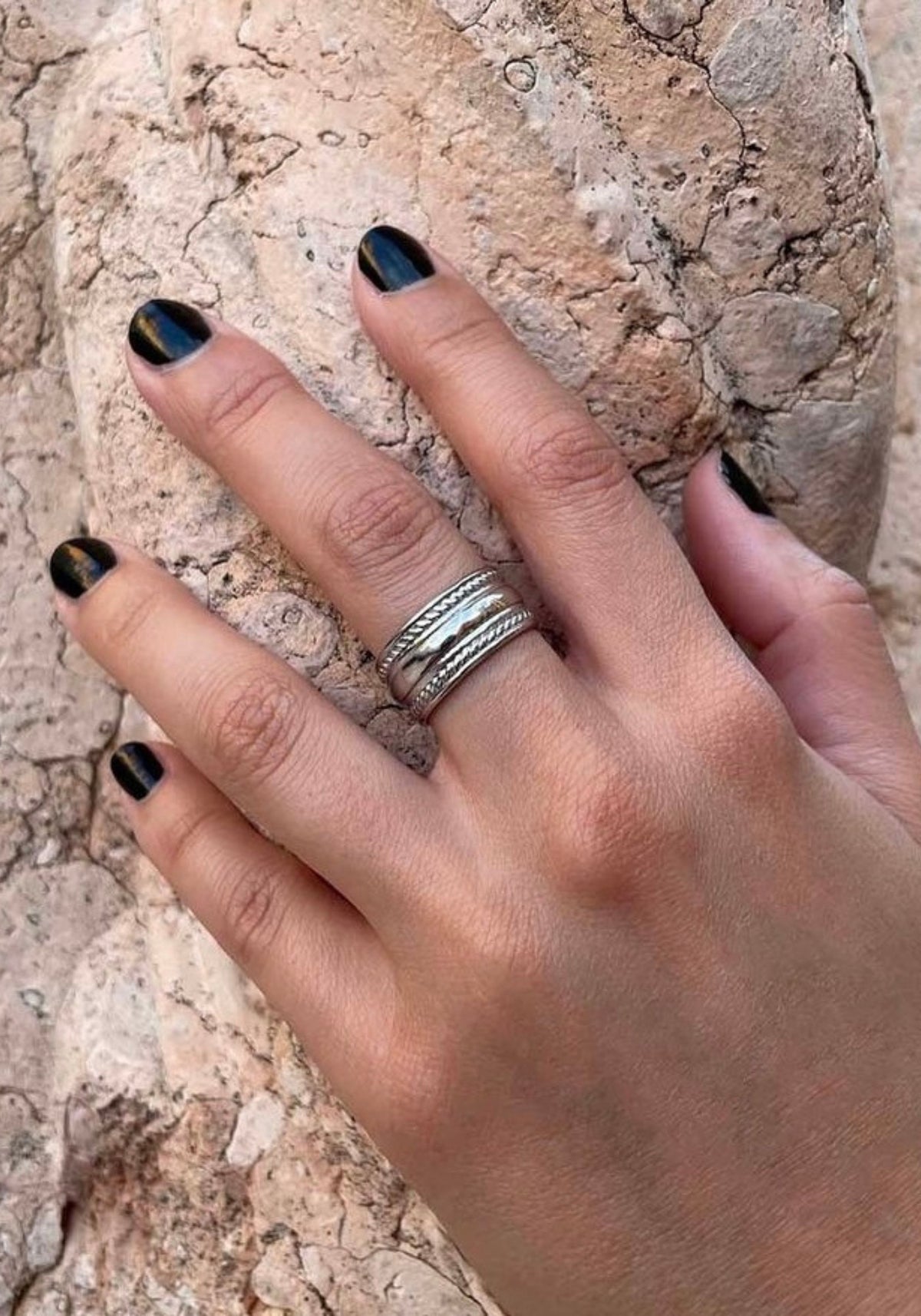 La femme a la main posée sur de la pierre et porte la bague Sabrina en argent de chez Caprice Paris