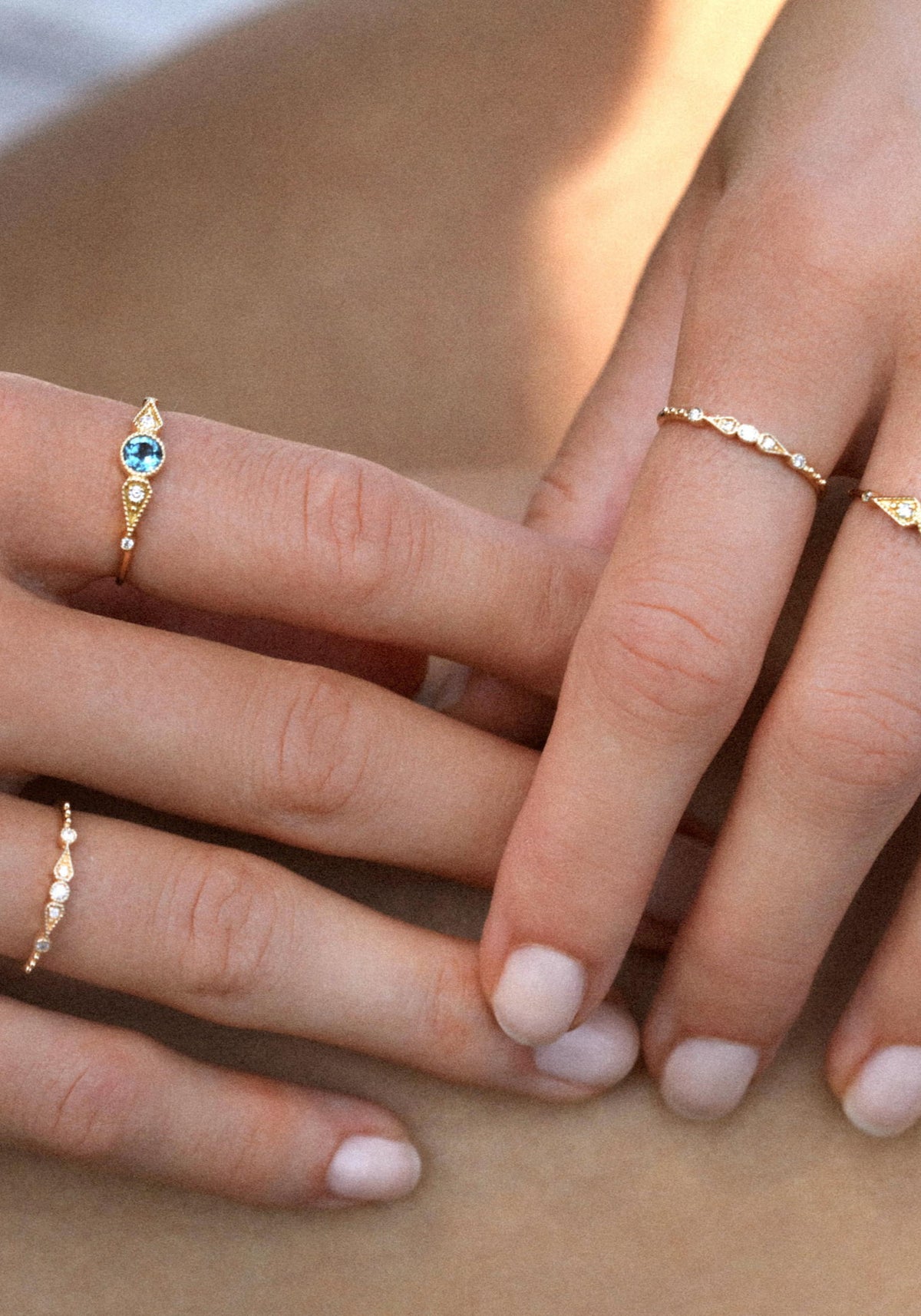 La femme porte la bague Stella 5 Diamants en or jaune de chez Angèle Brousse au niveau de son index et de son annulaire.