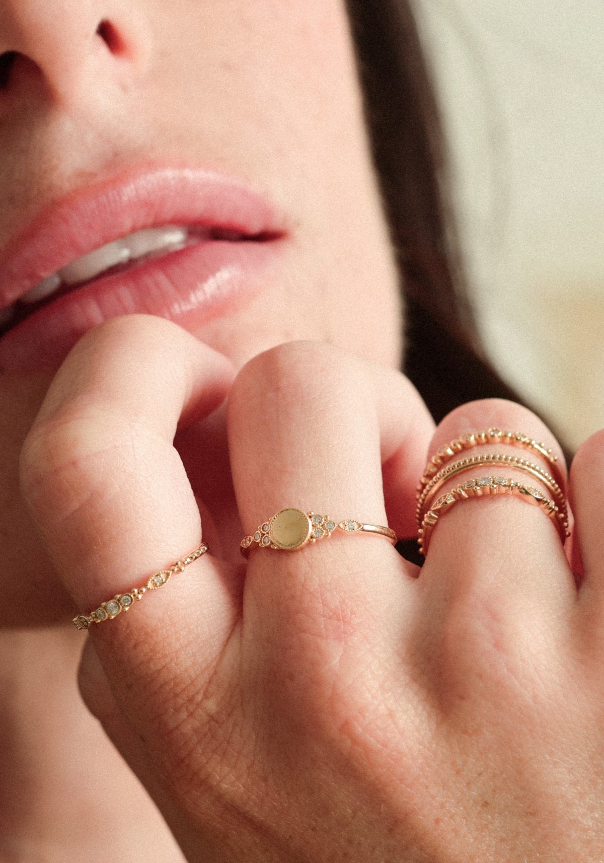 La femme porte la bague Susie Gold de chez Angèle Brousse tout en posant les doigts sur son menton.