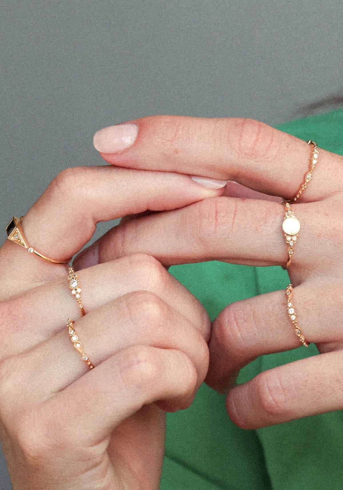 La femme porte la bague Susie Gold de chez Angèle Brousse tout en jouant avec ses doigts.