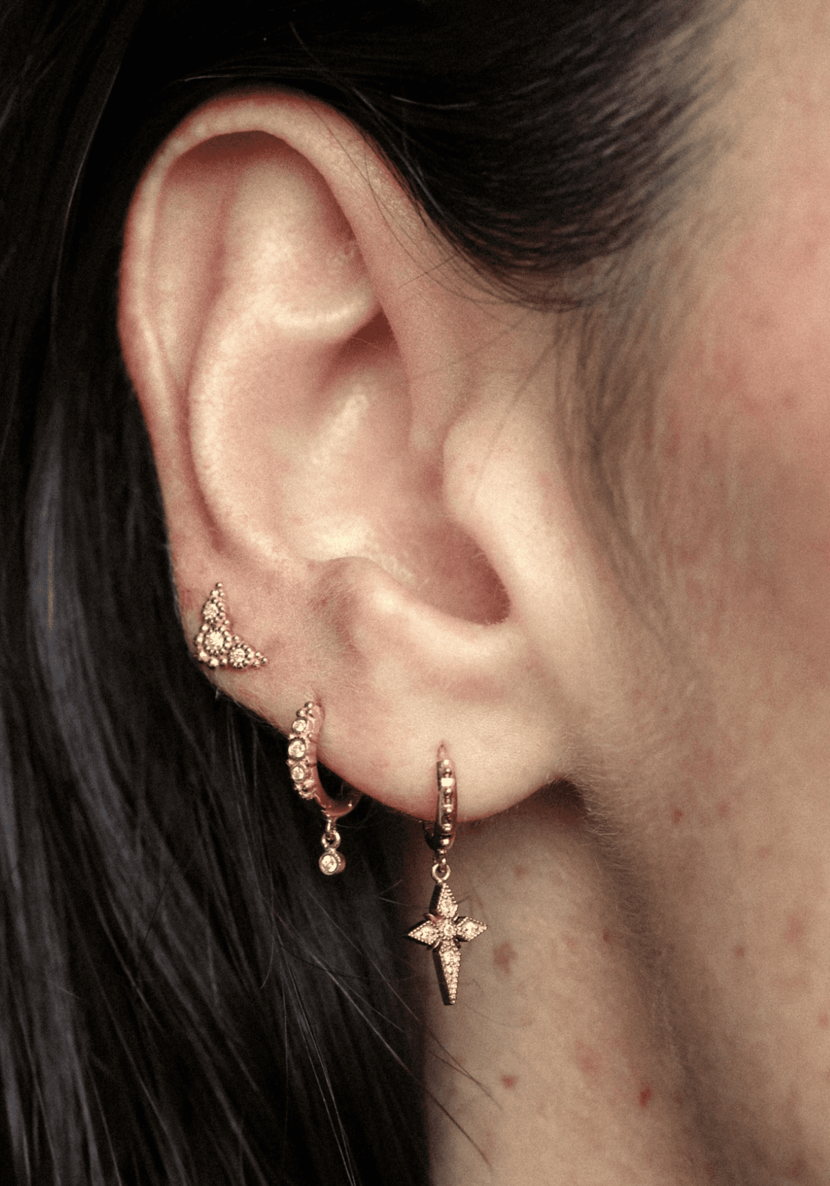 La femme porte la boucle d'oreille Puce Susie en or jaune de chez Angèle Brousse au niveau du troisième trou