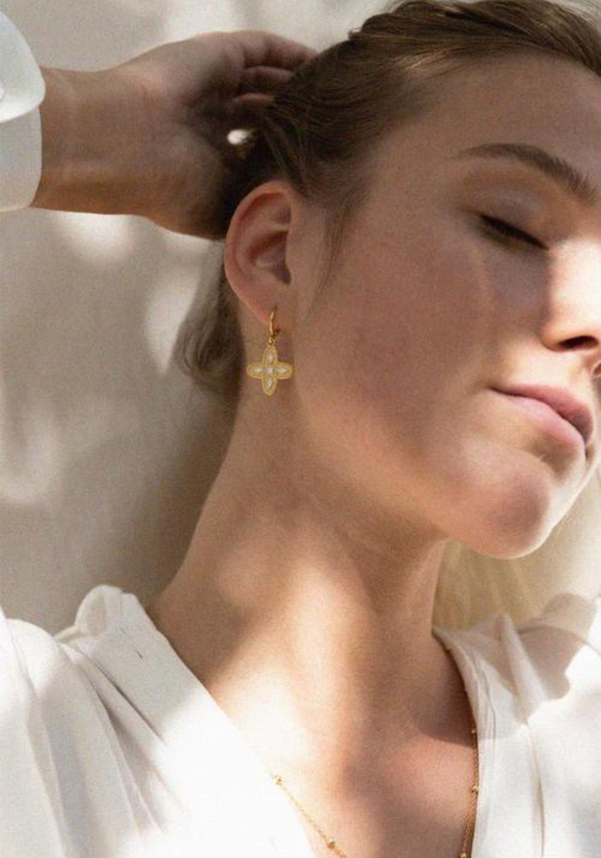 La femme porte les boucles d'oreilles Adriana écru de chez Bacci Paris