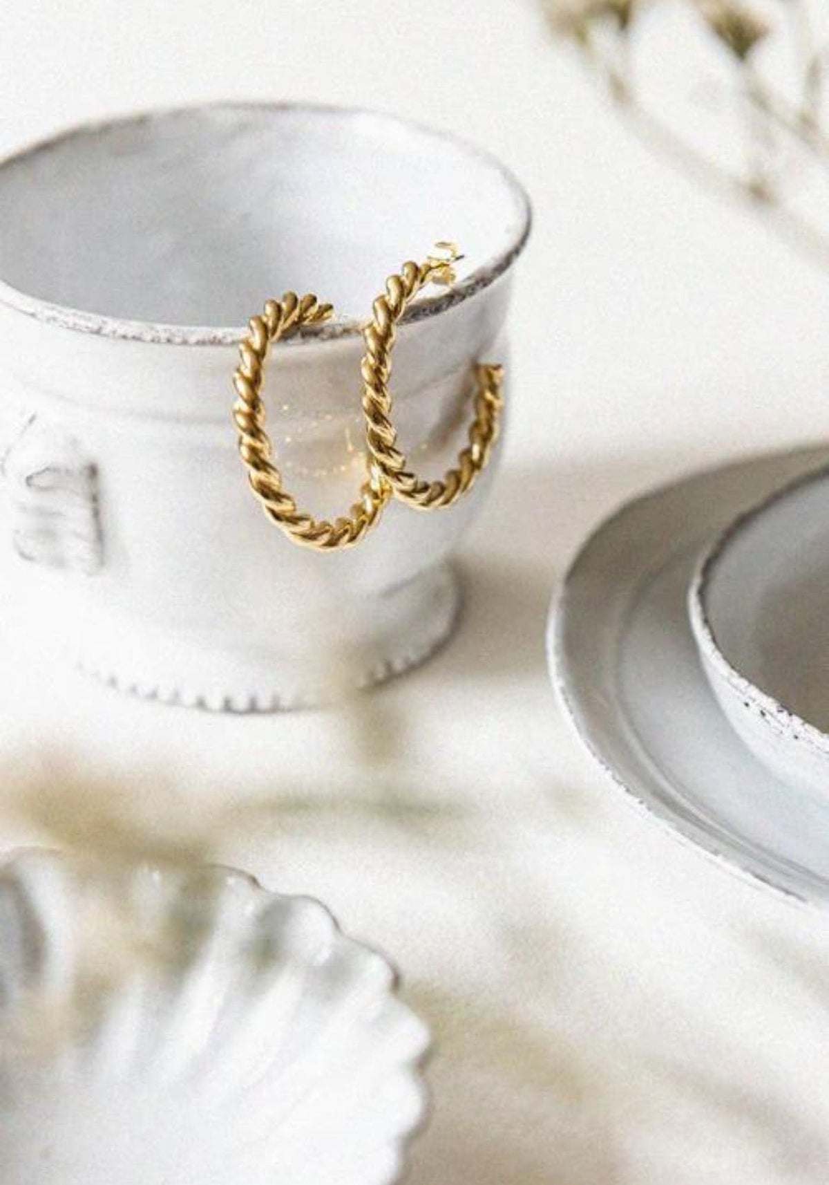 Les boucles d'oreilles Gabrielle de chez Bacci Paris sont posées sur le rebord d'une tasse