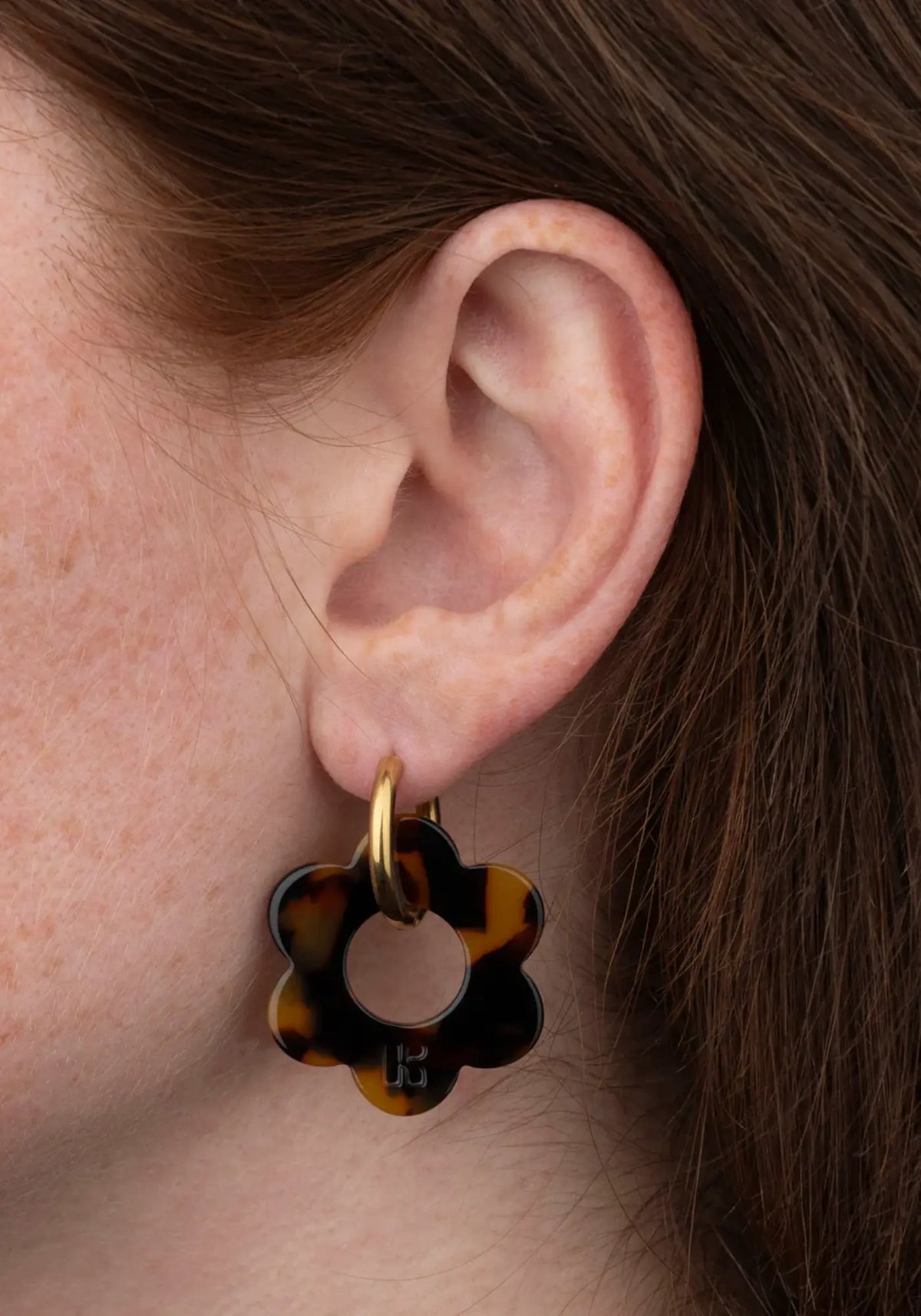 La femme porte les boucles d'oreilles fleurette écaille maxi de chez Kurage Ginza