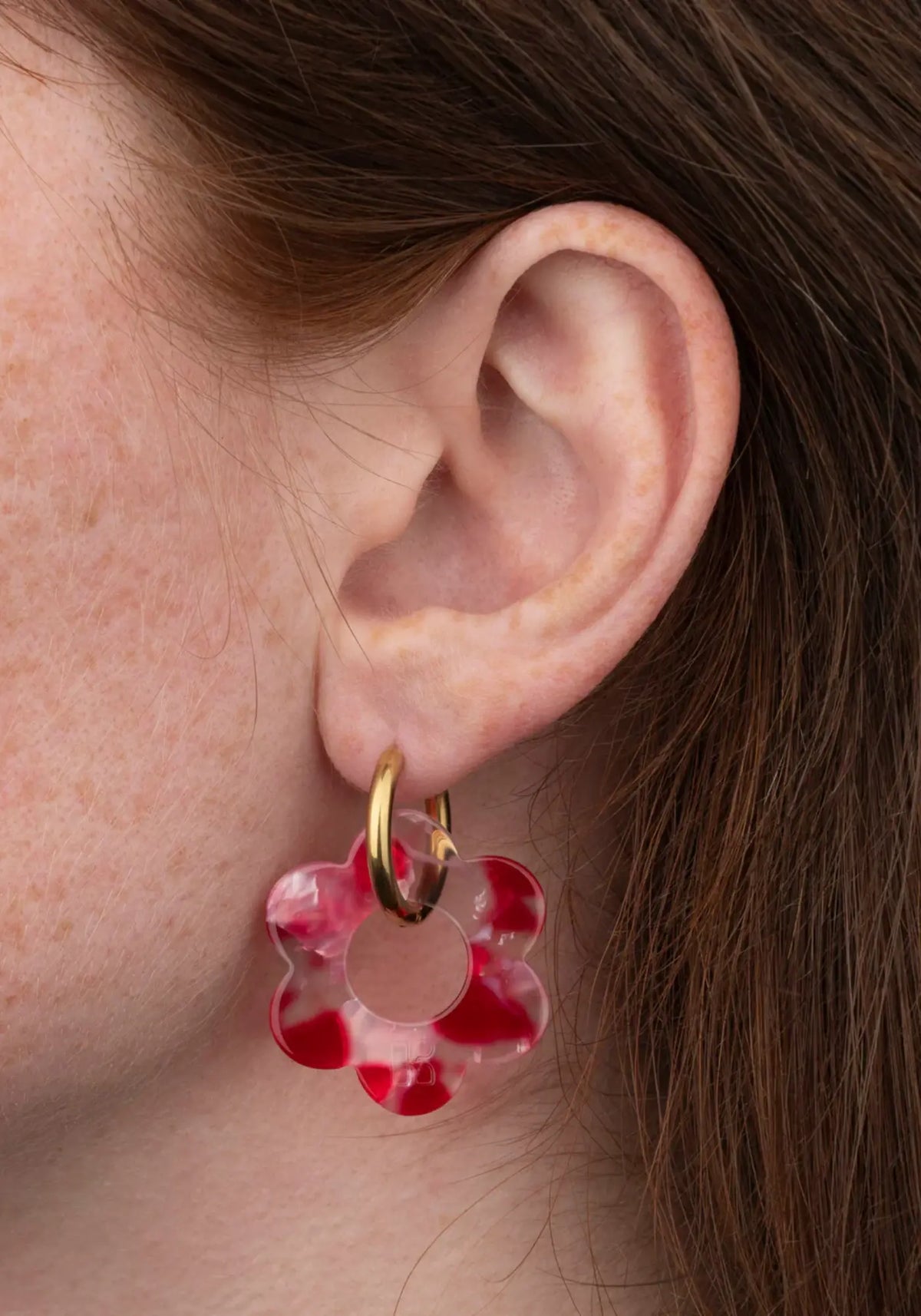 La femme porte les boucles d'oreilles fleurette rouge maxi de chez Kurage Ginza