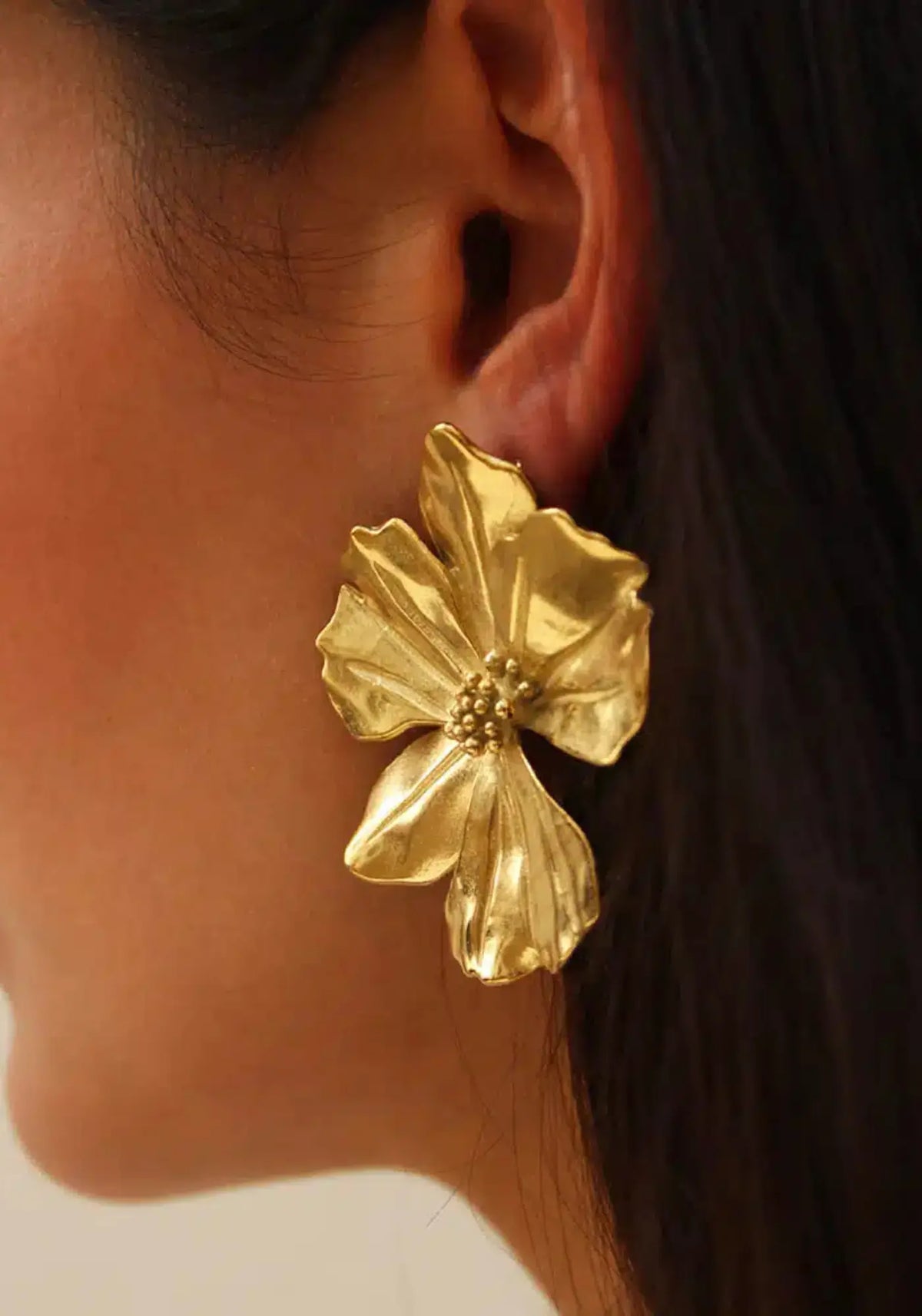 La femme porte les boucles d'oreilles Vicky Or de chez Caprice Paris 