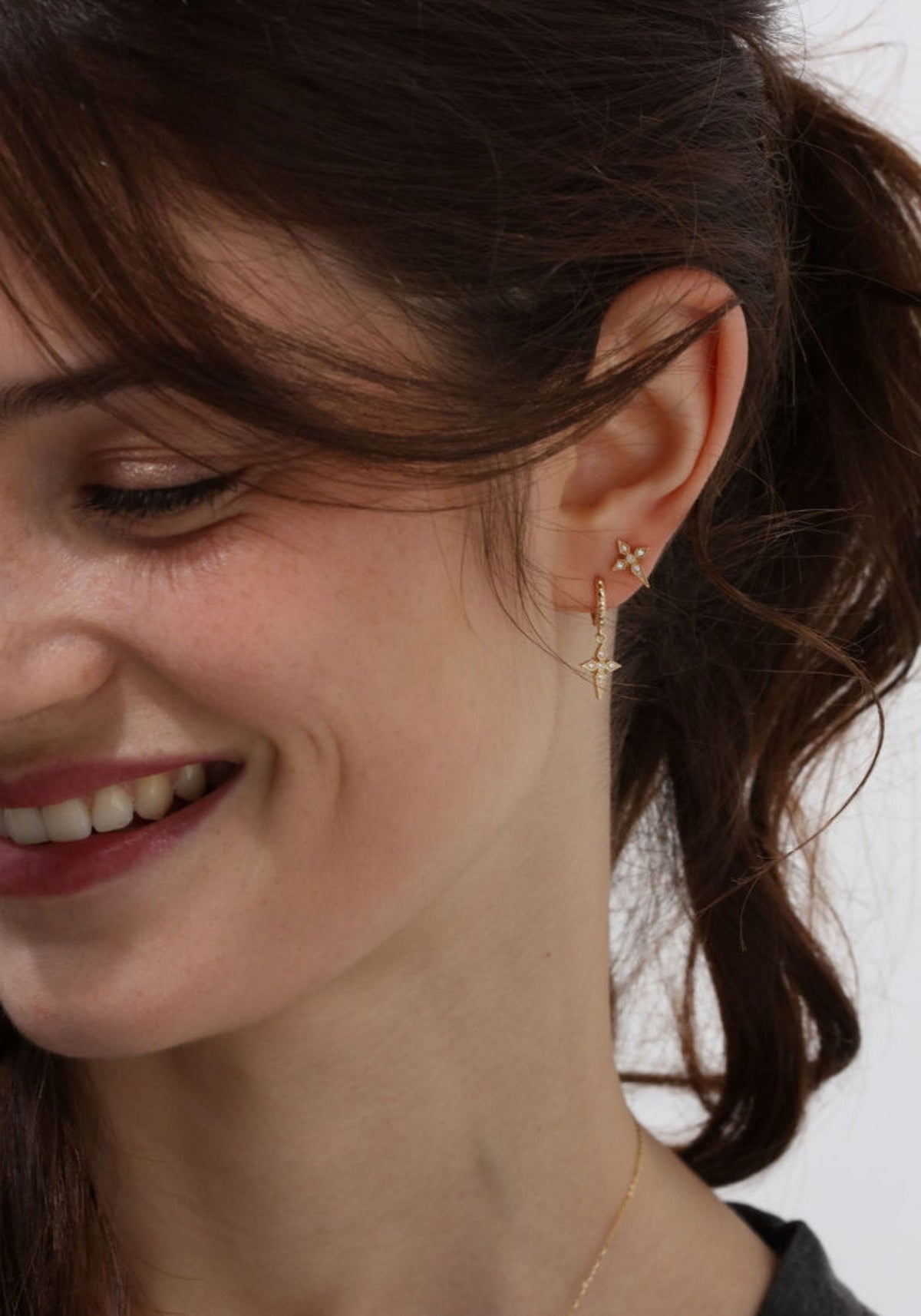 La femme porte la boucle d'oreilles puce croix saintes en or jaune de chez Angèle Brousse