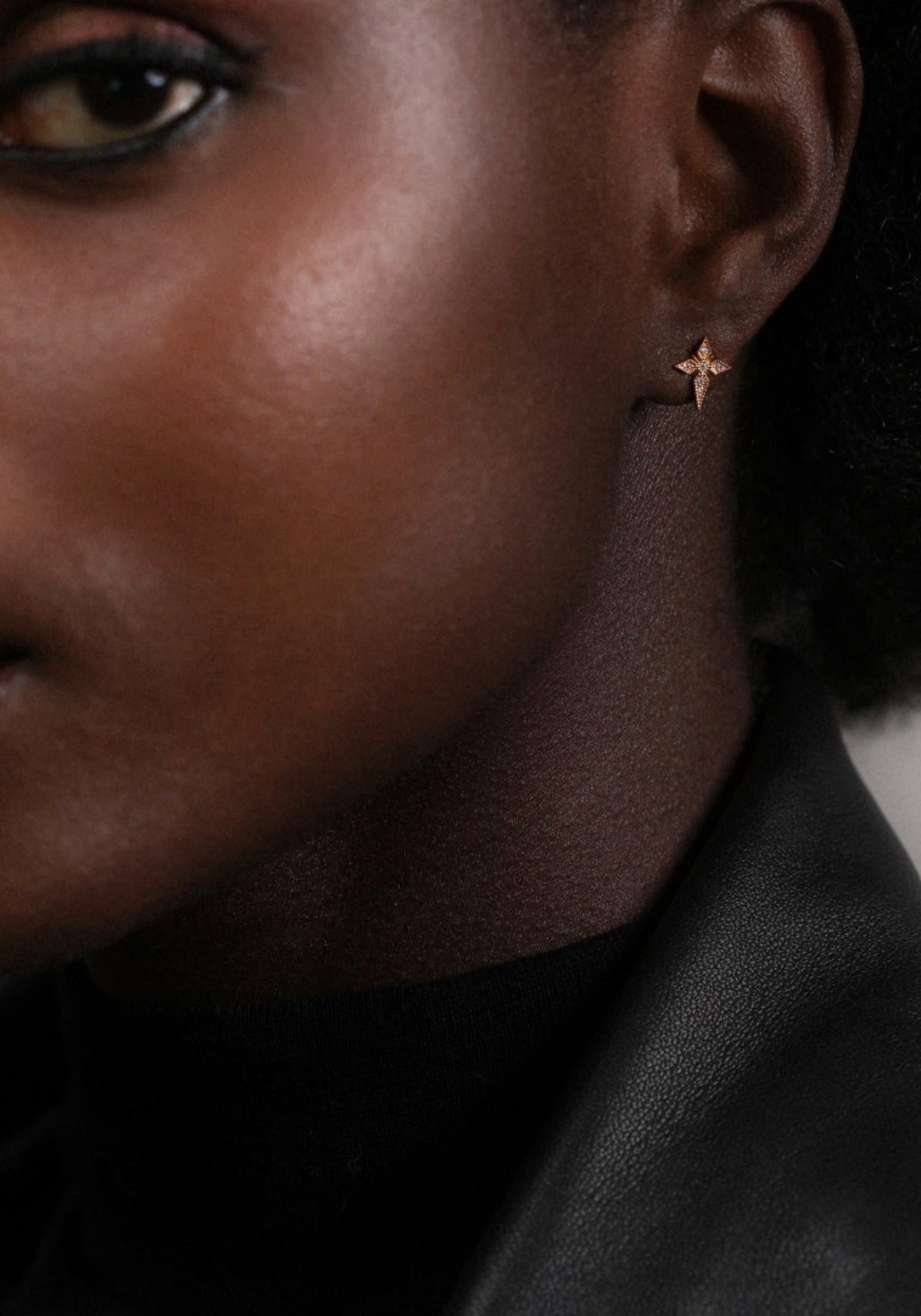 La femme porte la boucle d'oreilles puce croix saintes en or jaune de chez Angèle Brousse
