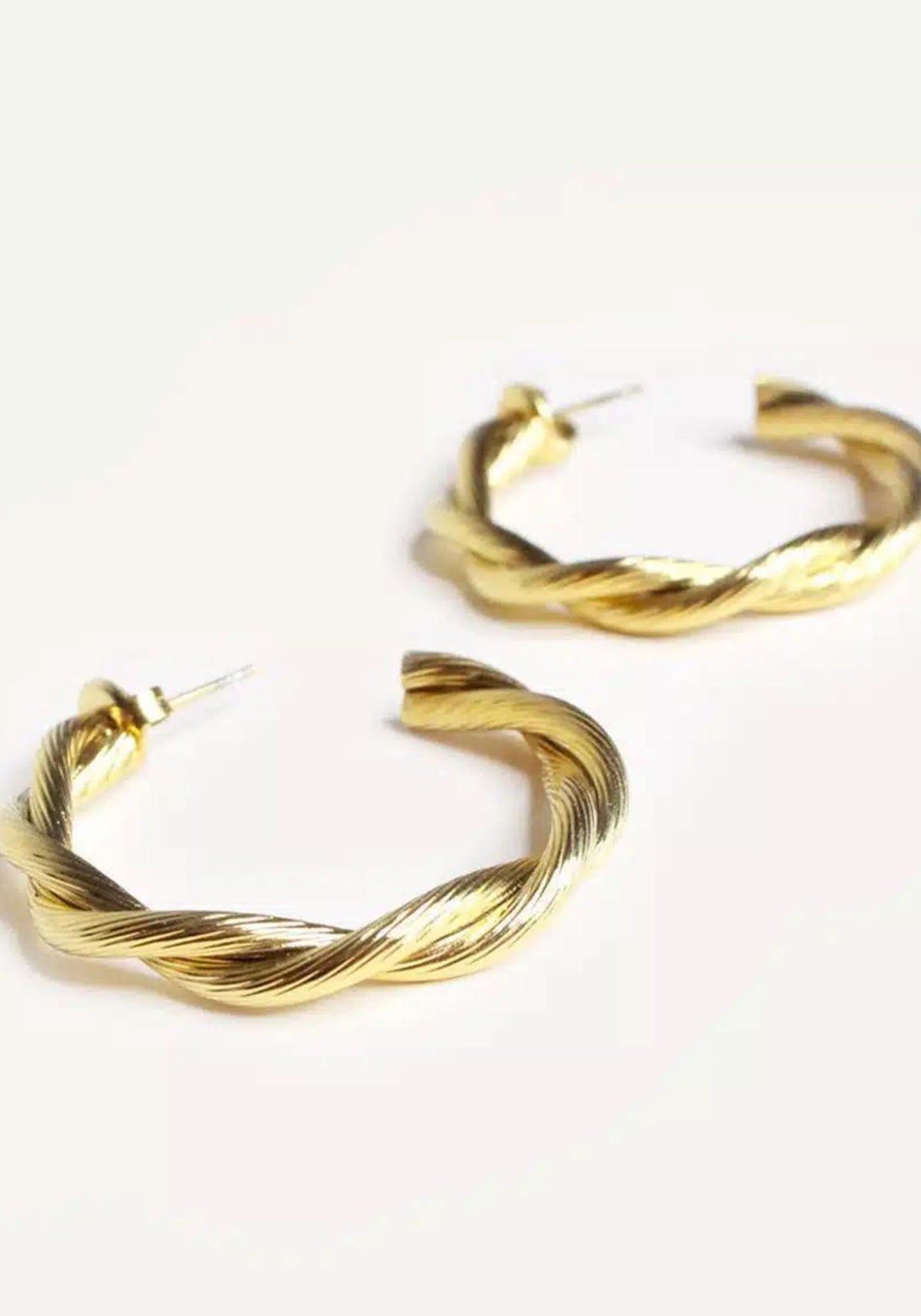 Boucles d'oreilles Demeter dorées sur fond blanc de chez Caprice Paris