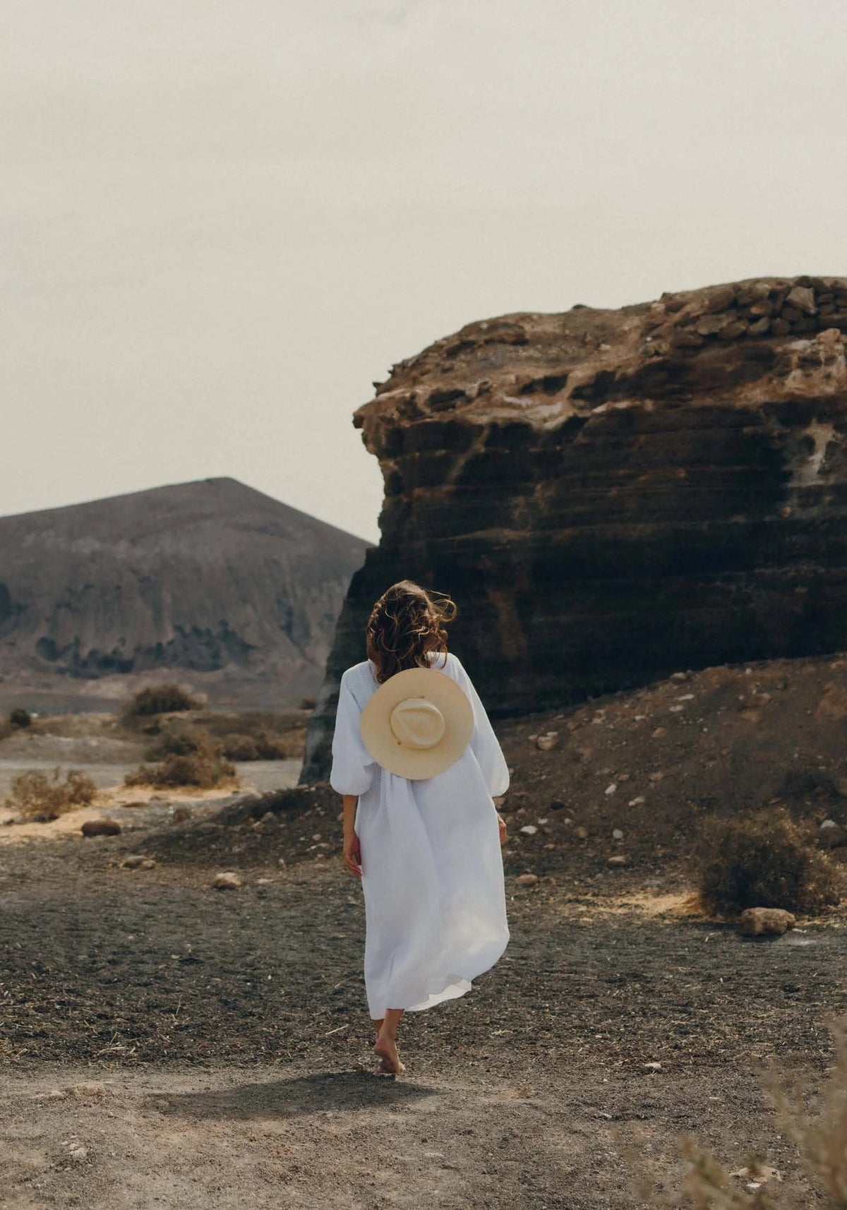 La femme porte sur son dos le chapeau de paille avec chaîne Livy Junior natural de chez Van Palma