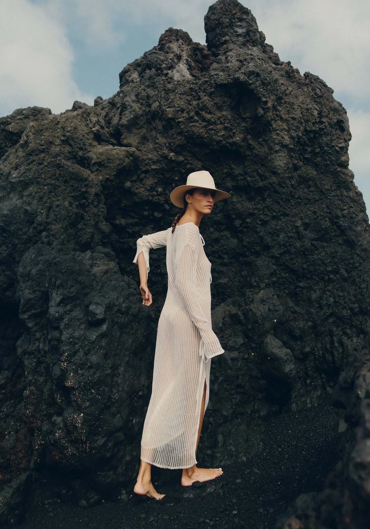 La femme porte le chapeau de paille Diana avec broche dorée natural de chez Van Palma