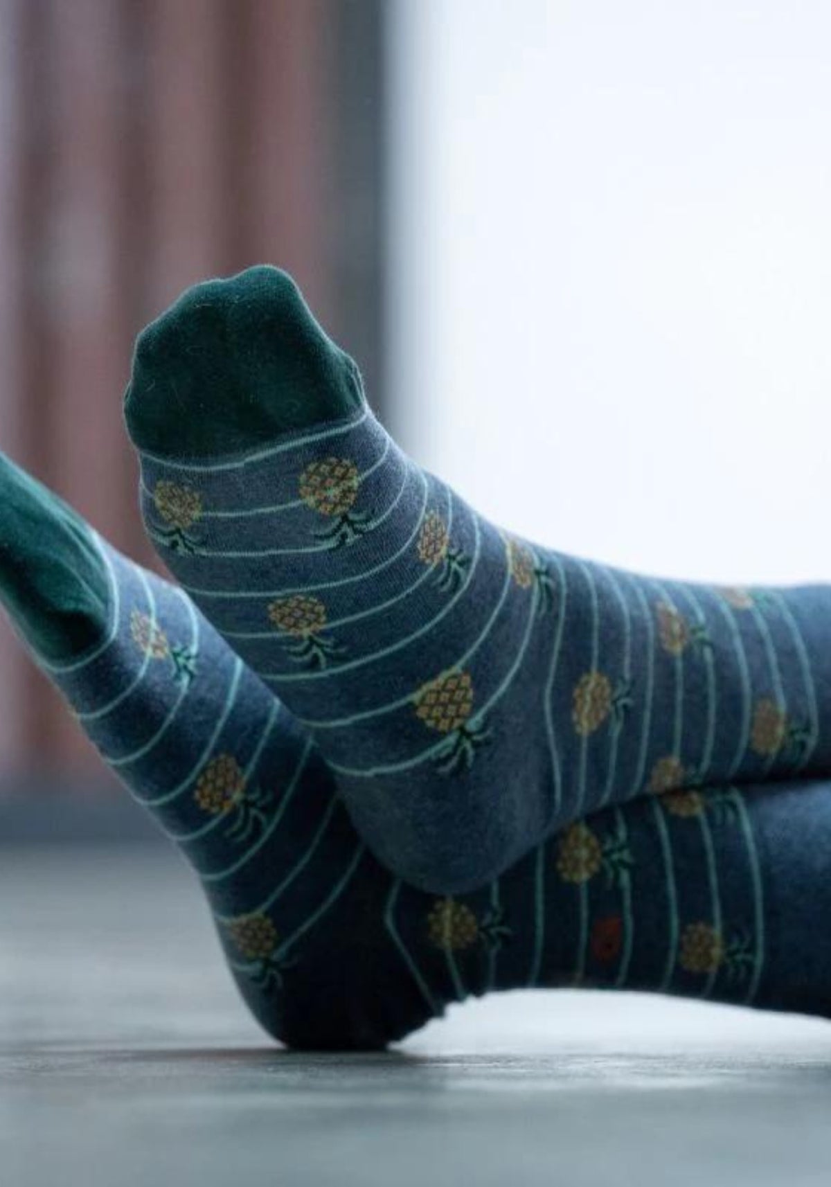 L'homme porte les chaussettes fantaisie ananas de chez Billybelt en ayant les jambes croisées