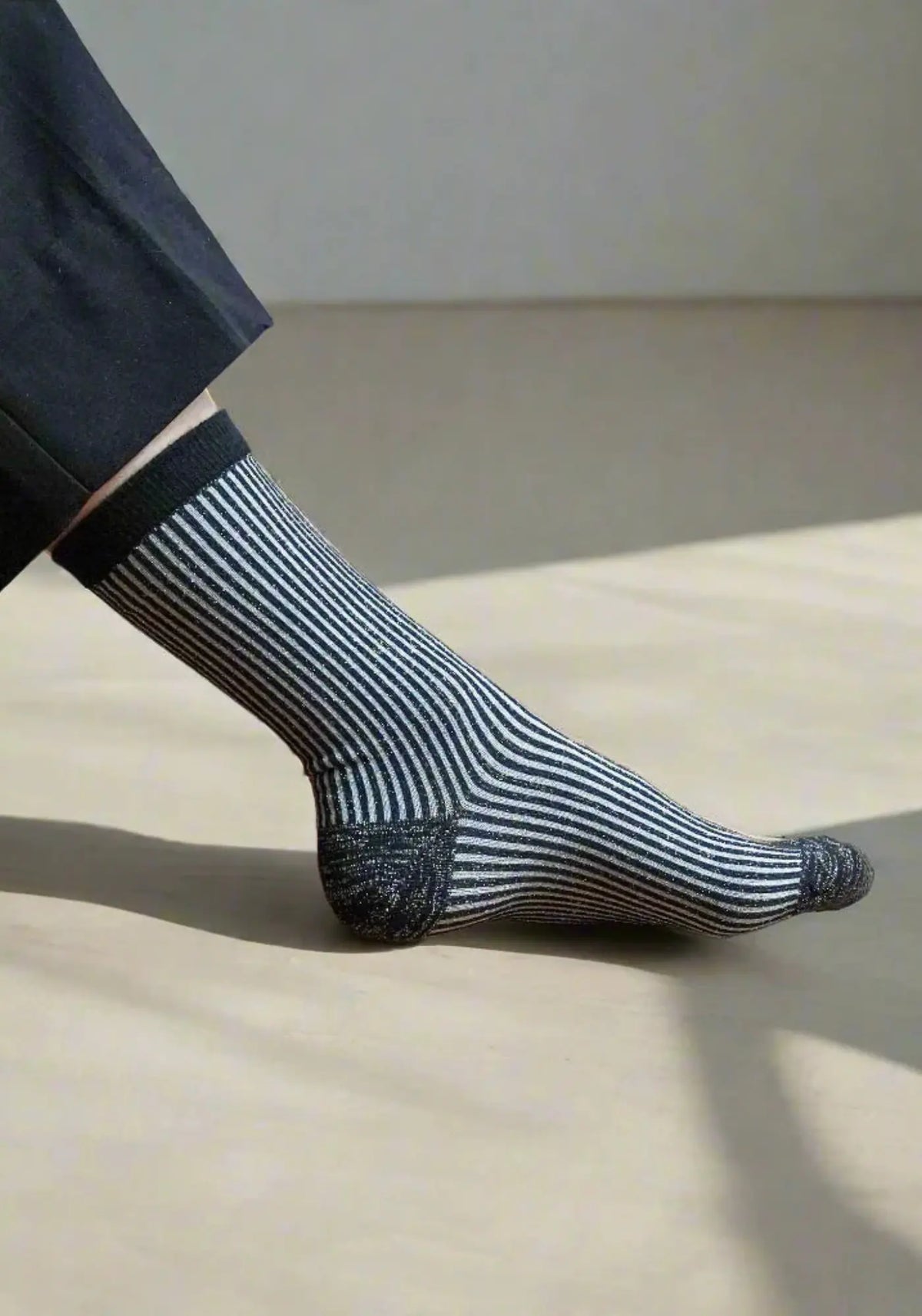 Le mannequin porte les chaussettes lurex à rayures noires de chez Klue