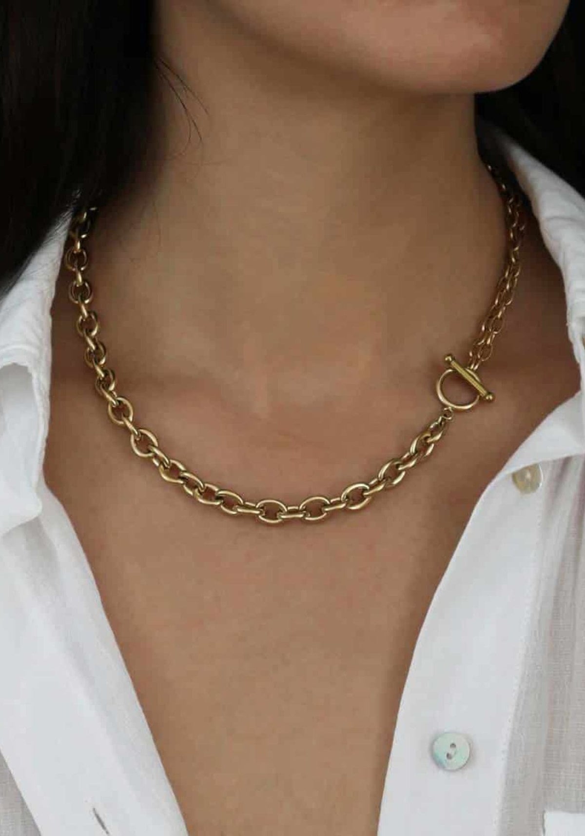 La femme porte le collier en maillons Rosalie de chez Caprice Paris. 
