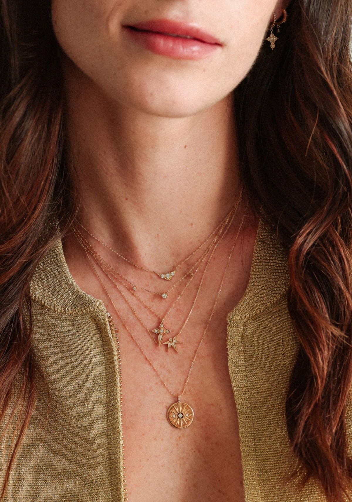 La femme porte une compostions de divers bijoux Angèle Brousse dont le collier Susie en or jaune