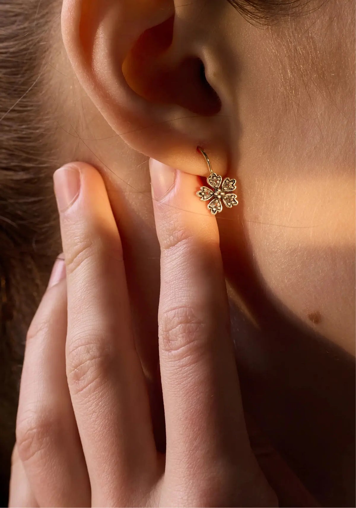 La femme porte les boucles d'oreilles Daisy de chez Dorothée Sausset
