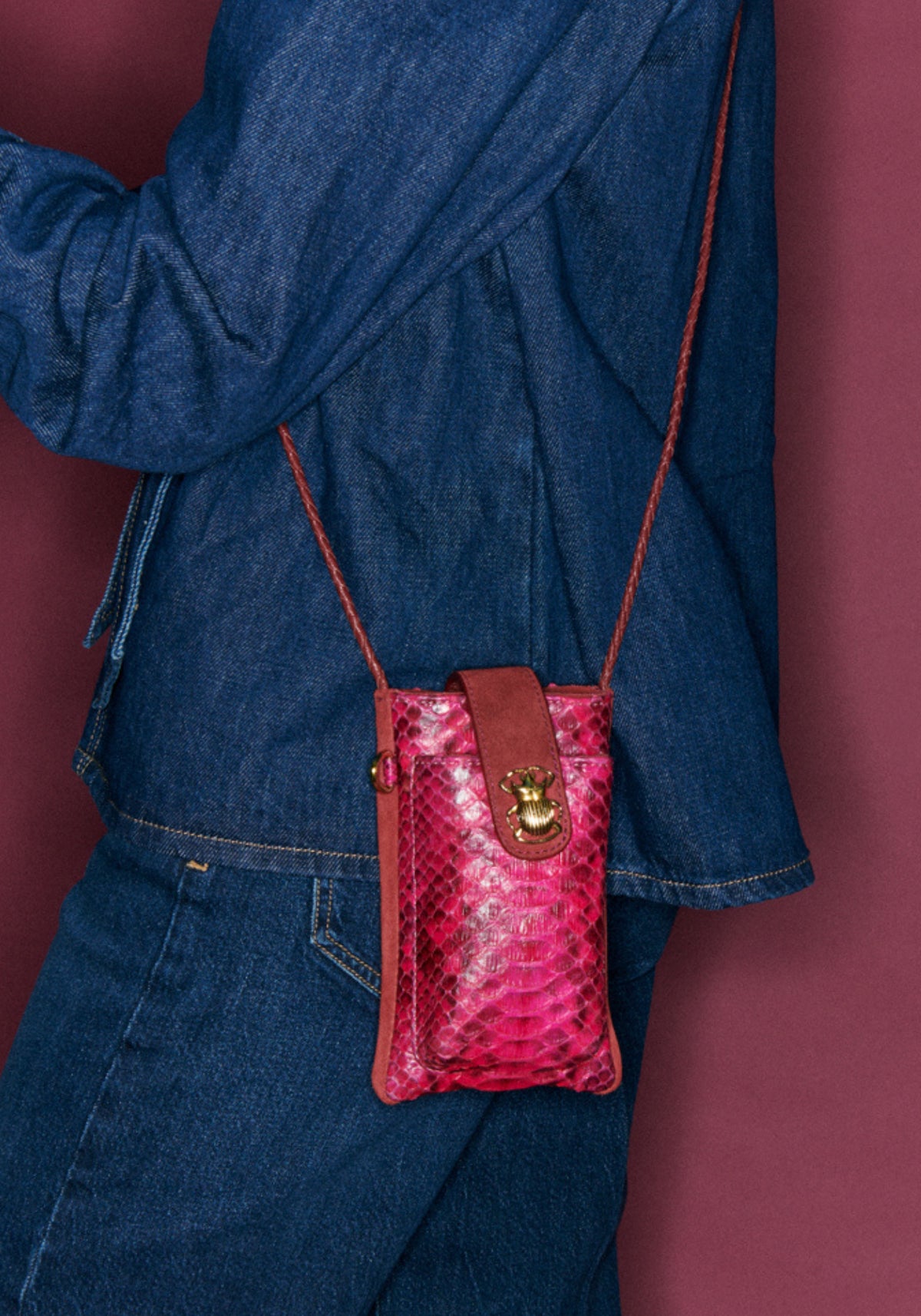 La femme porte l'étui de téléphone Marcus celosia rose de chez Claris Virot