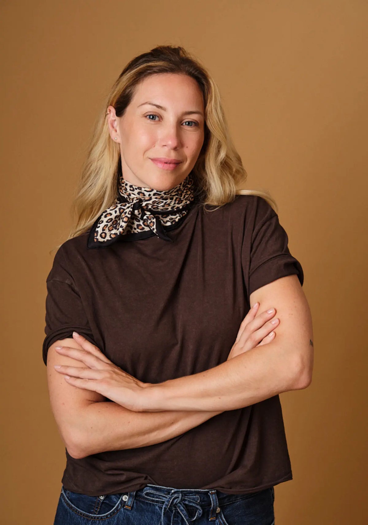 La femme porte autour de son coup le foulard léopard pure soie de chez Emily's Pillow