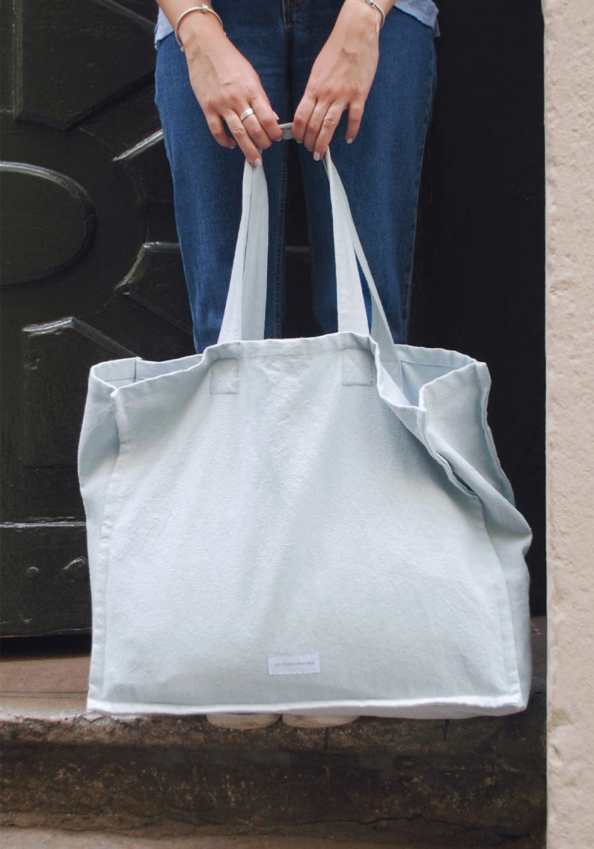 La femme tient le grand sac cabas bleu subtil de chez Les Pensionnaires