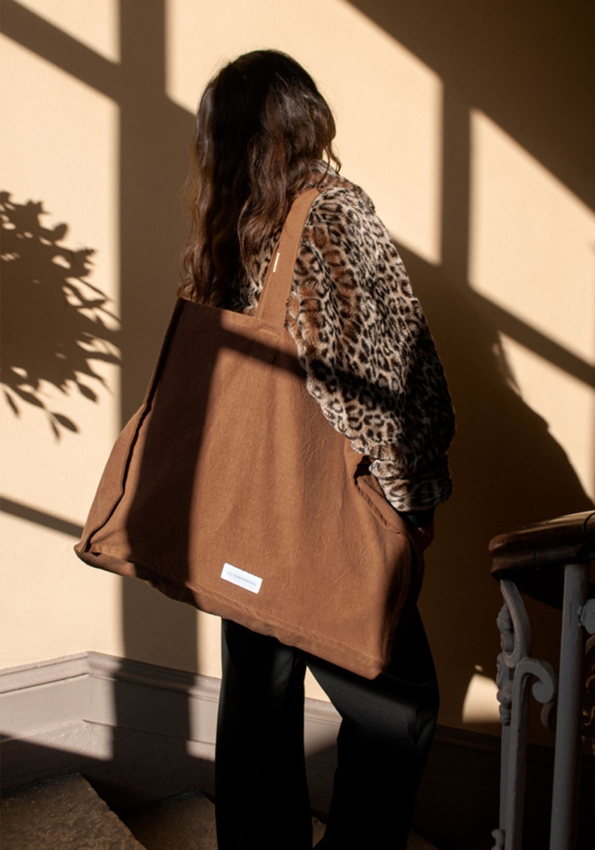 La femme porte le grand sac cabas noisette de chez Les Pensionnaires
