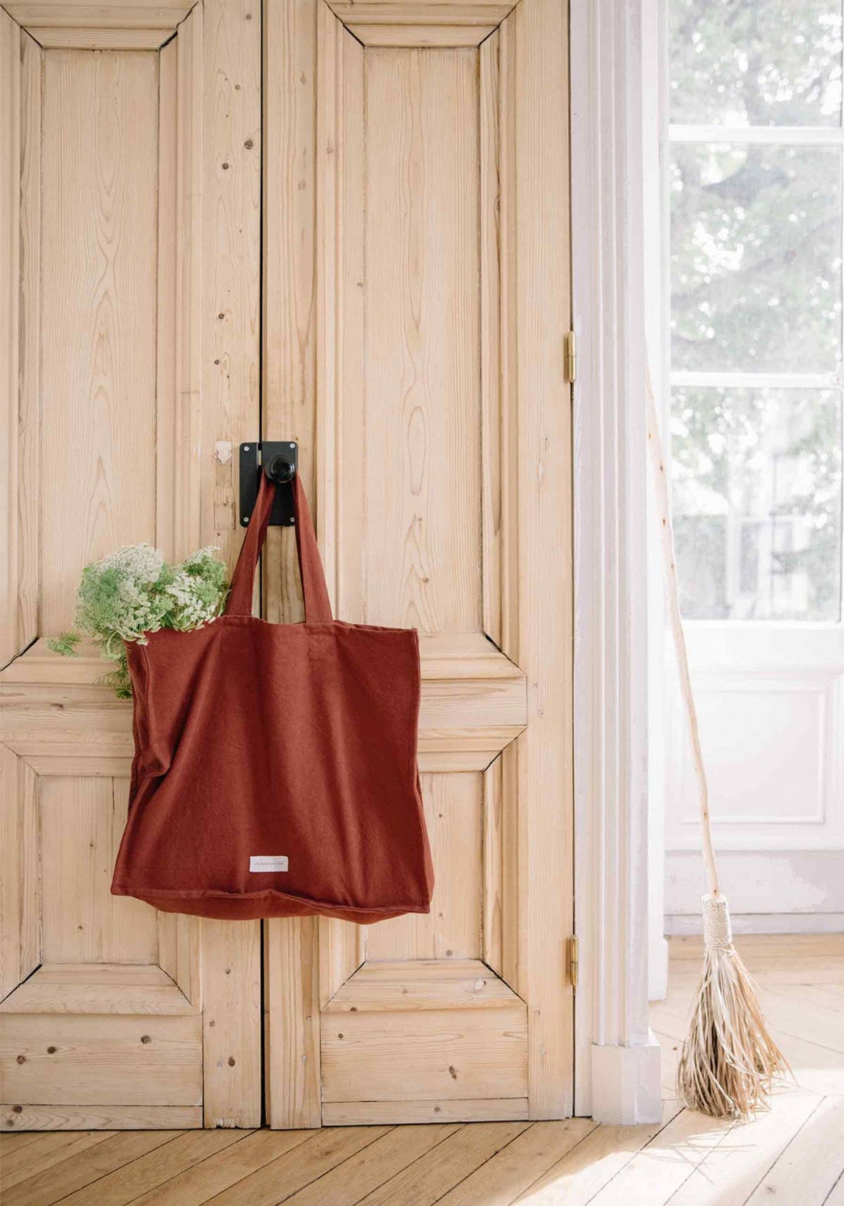 Le grand sac cabas rouille de chez Les Pensionnaires suspendu à une poignée de porte