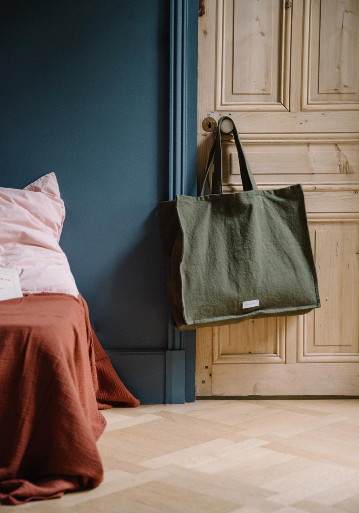 Le grand sac cabas vert câpre de chez Les Pensionnaires suspendu à une poignée de porte