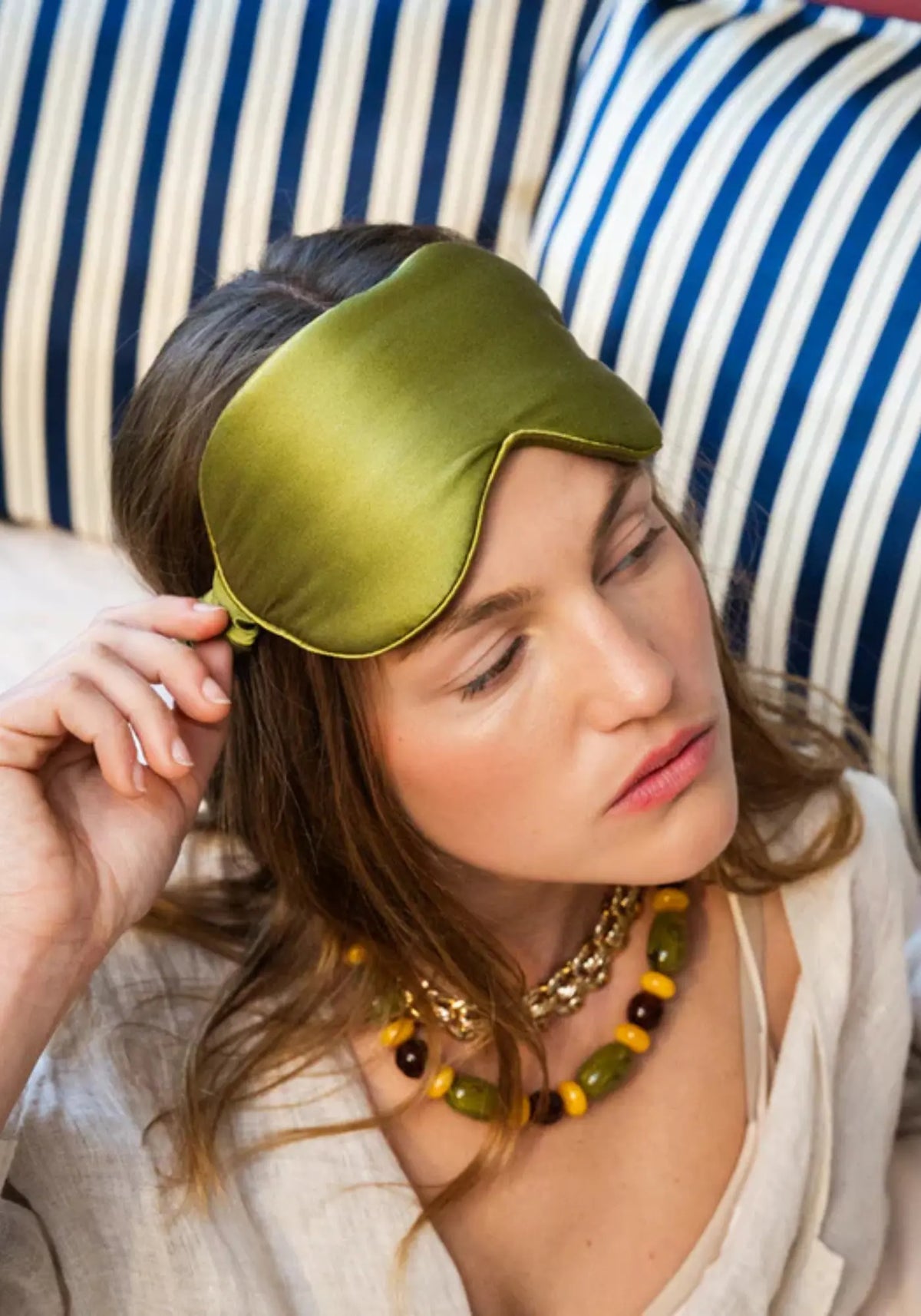 La femme porte le masque de nuit en soie vert mousse de chez Emily's Pillow