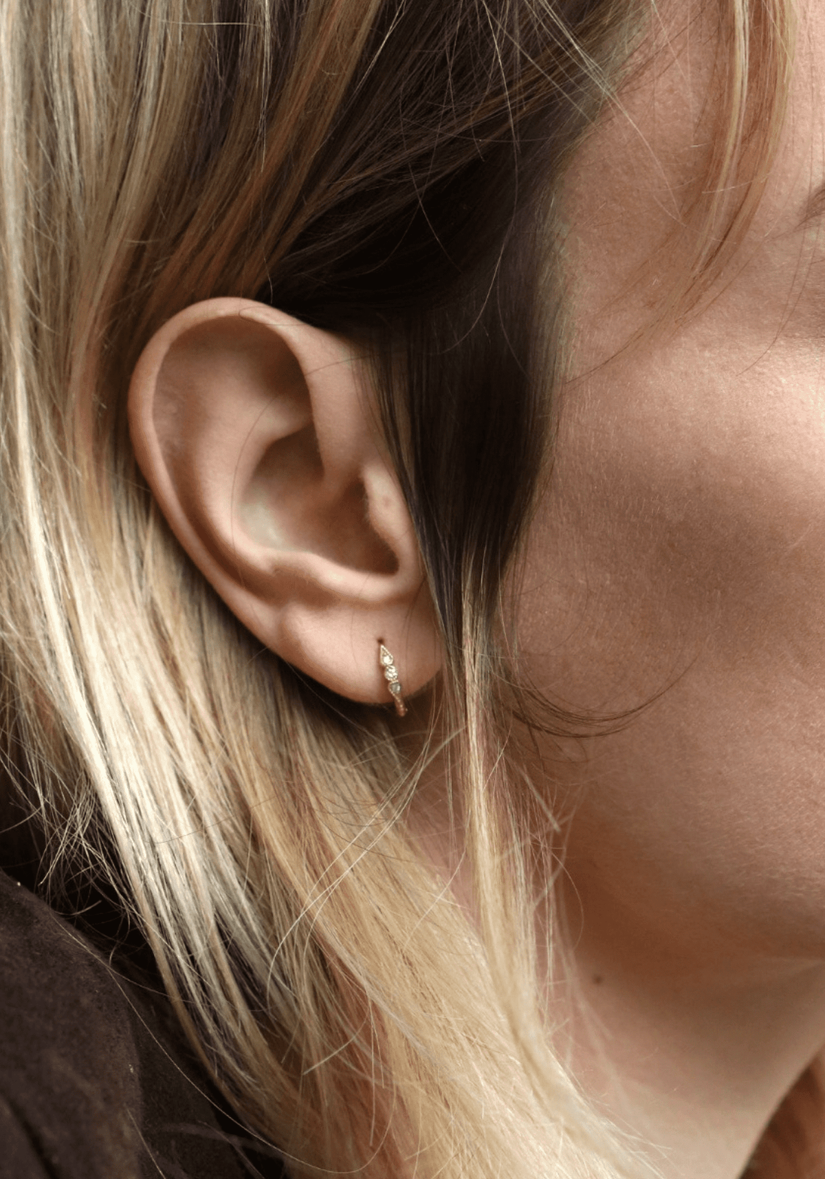 La femme porte la mini créole 3 diamants Stella en or jaune de chez Angèle Brousse