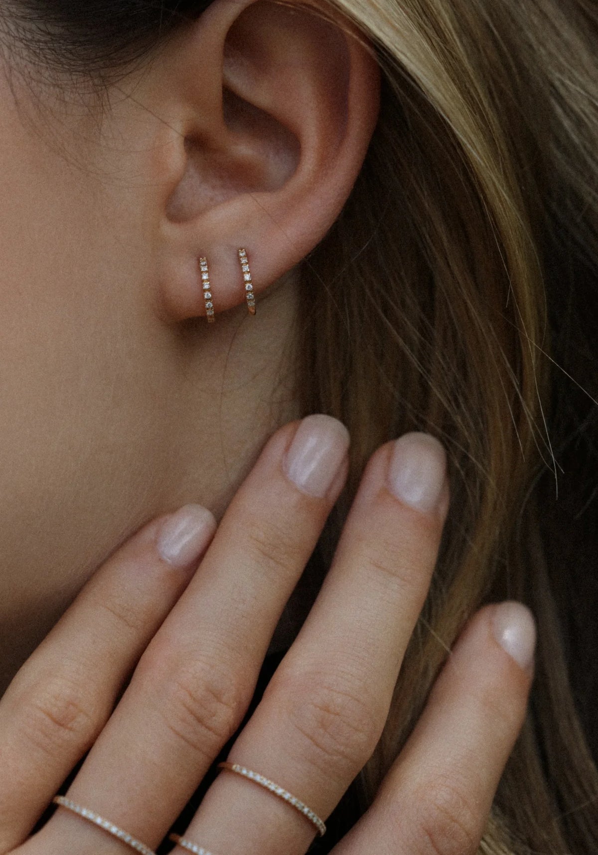 La femme porte les deux créoles en or jaune Dita de chez Angèle Brousse sur la même oreille