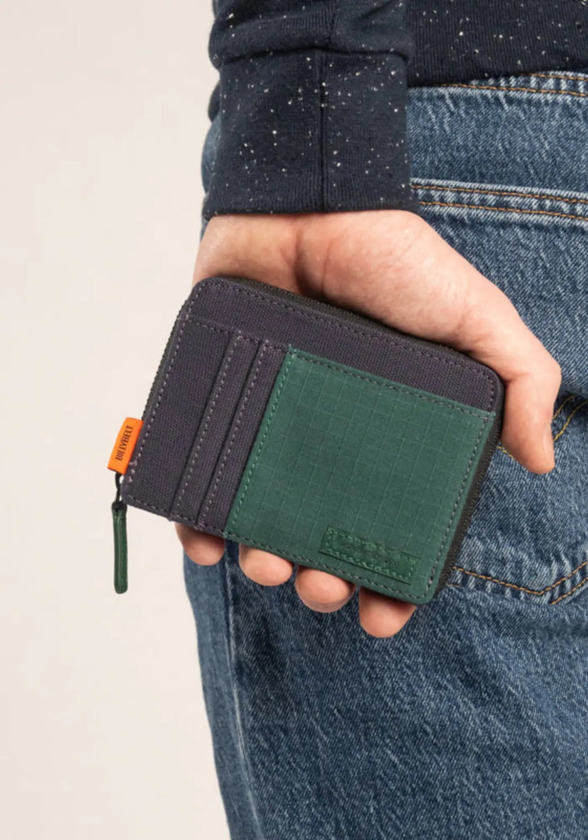 L'homme porte le portefeuille marine et vert de chez Billy Belt