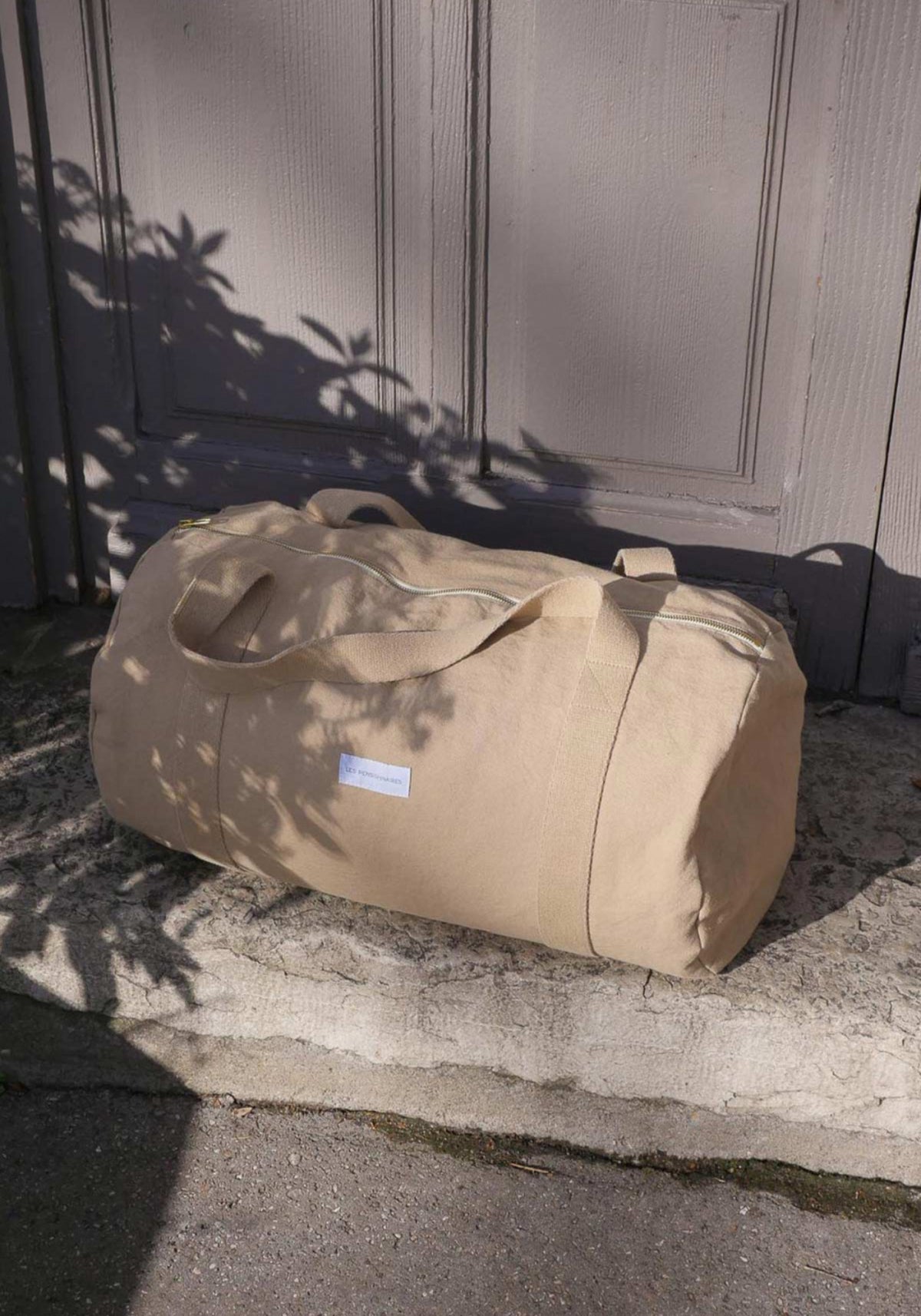 Le sac bowling beige sable de chez Les Pensionnaires posé sur une marche en pierre