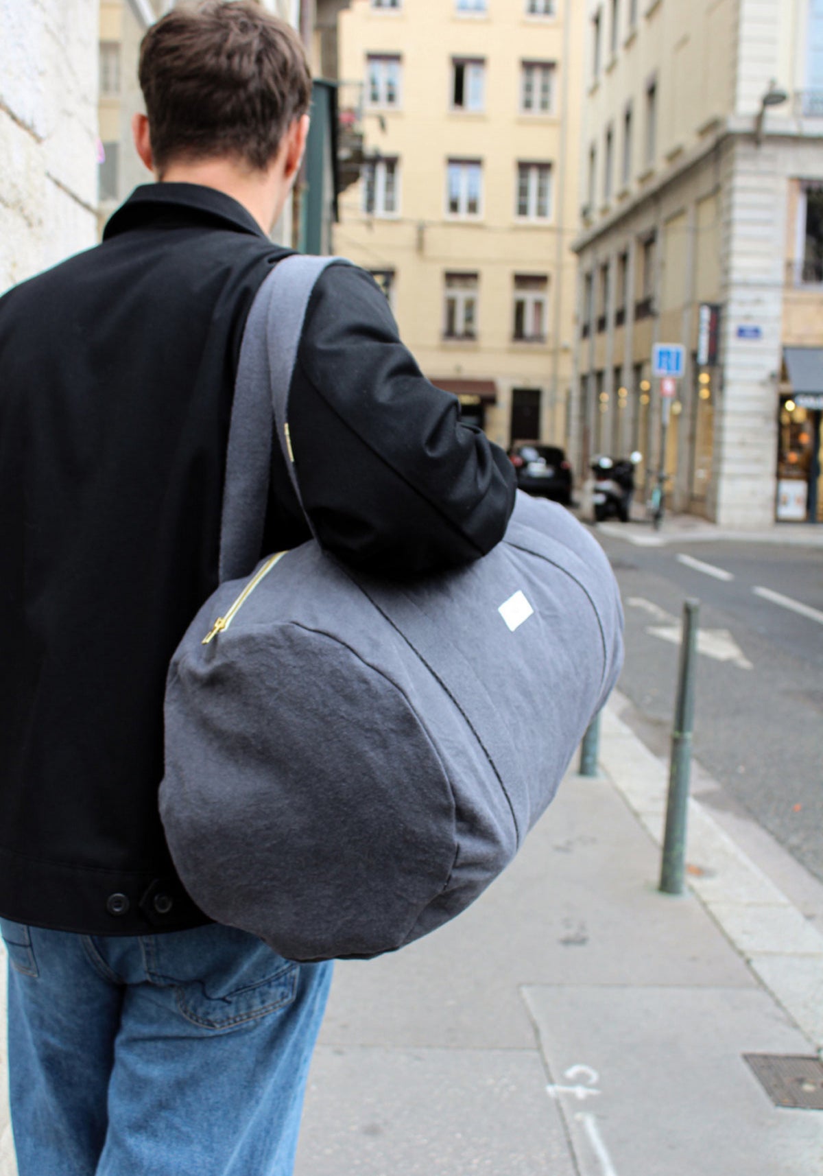 L'homme de dos porte sur son épaule le sac bowling gris ardoise de chez Les Pensionnaires