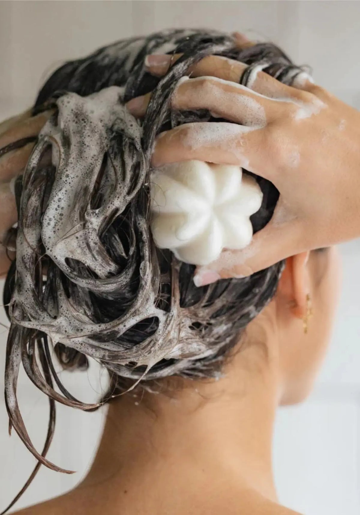 La femme se lave les cheveux avec le shampoing solide doux de chez Umai
