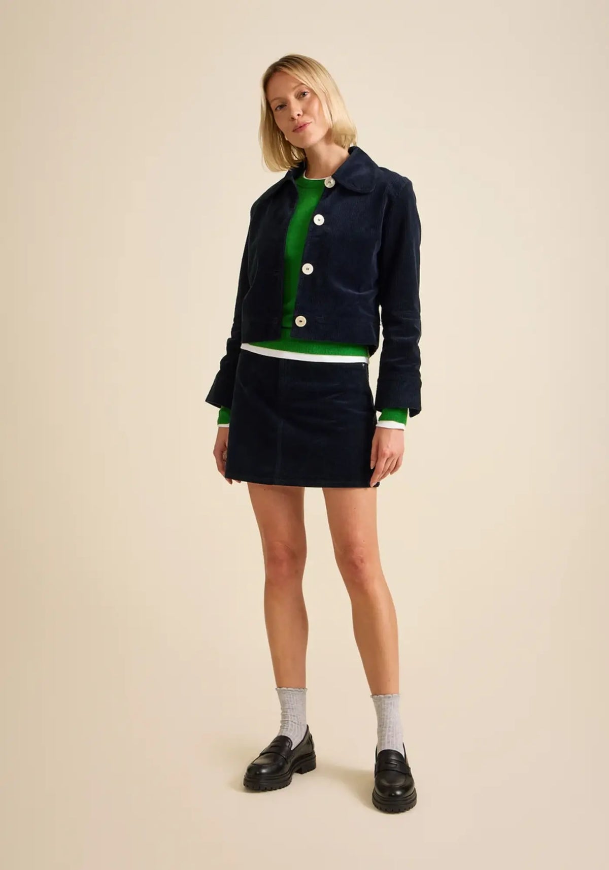 La femme porte la veste courte en velours daisy coloris navy de chez Côtelé Paris 