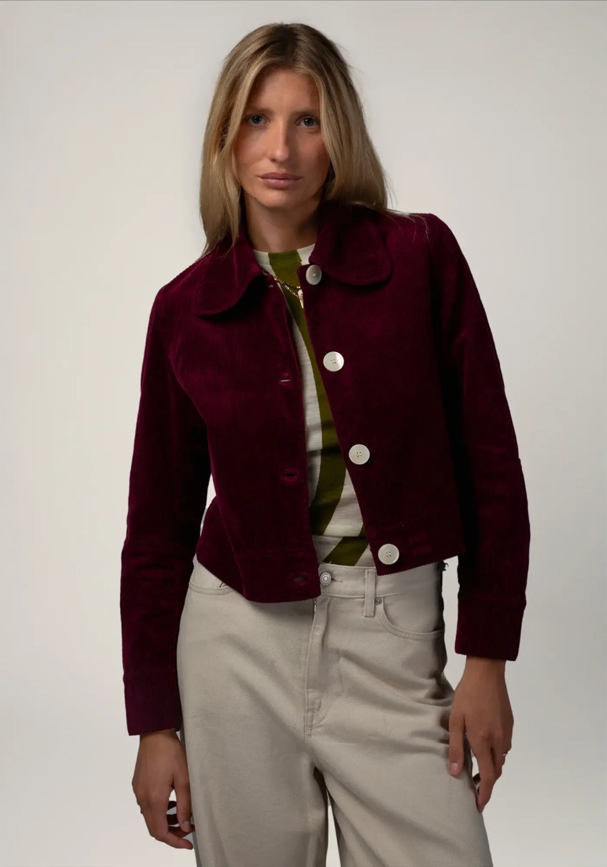 La femme porte la veste courte en velours daisy coloris prune de chez Côtelé Paris 